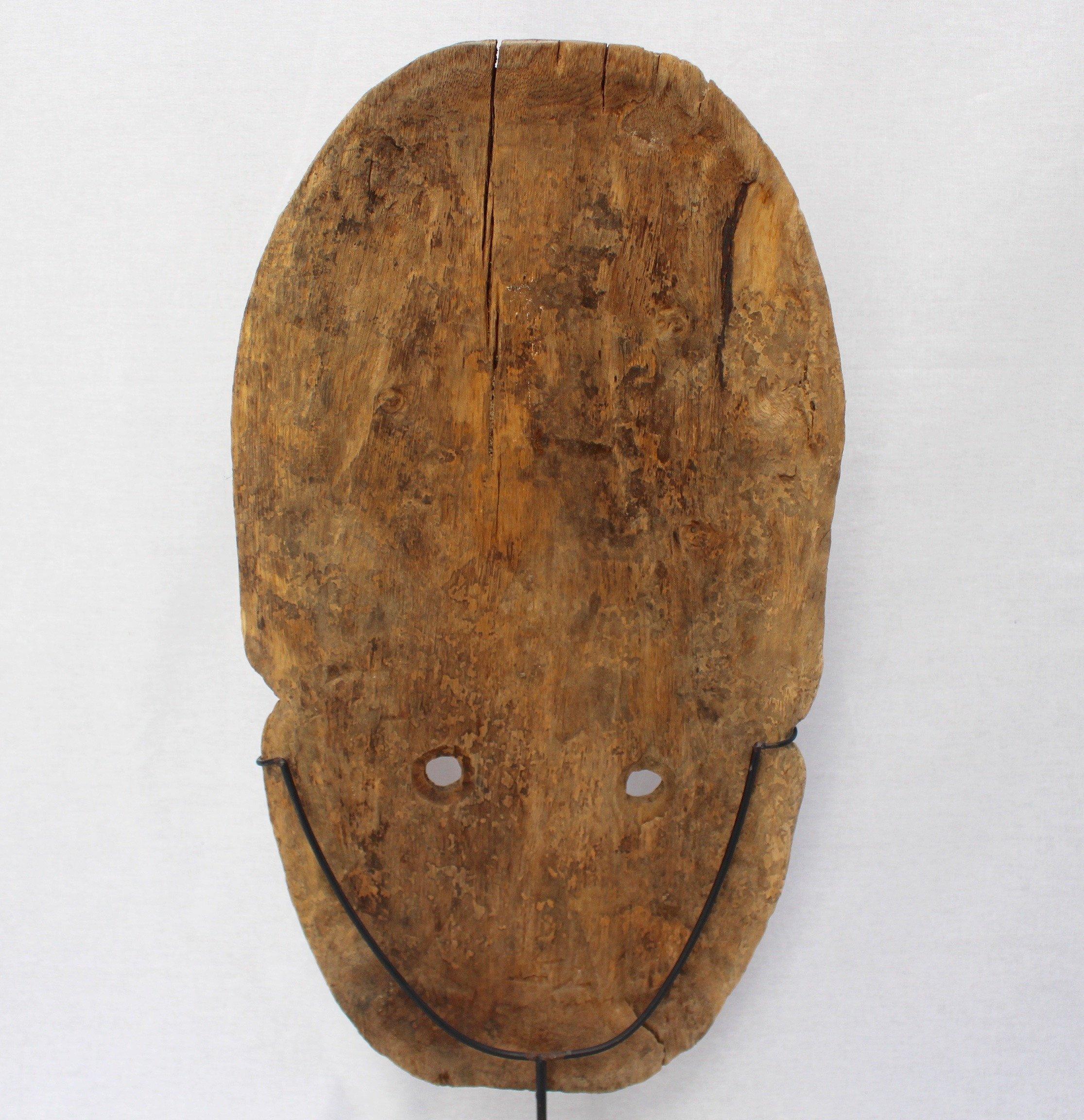 Timor Island sculpted wooden traditional mask (early 20th century) on contemporary metal stand. This is a large mask of a male figure with pronounced facial features and two circular holes as eyes and decorative headdress. The island of Timor gave
