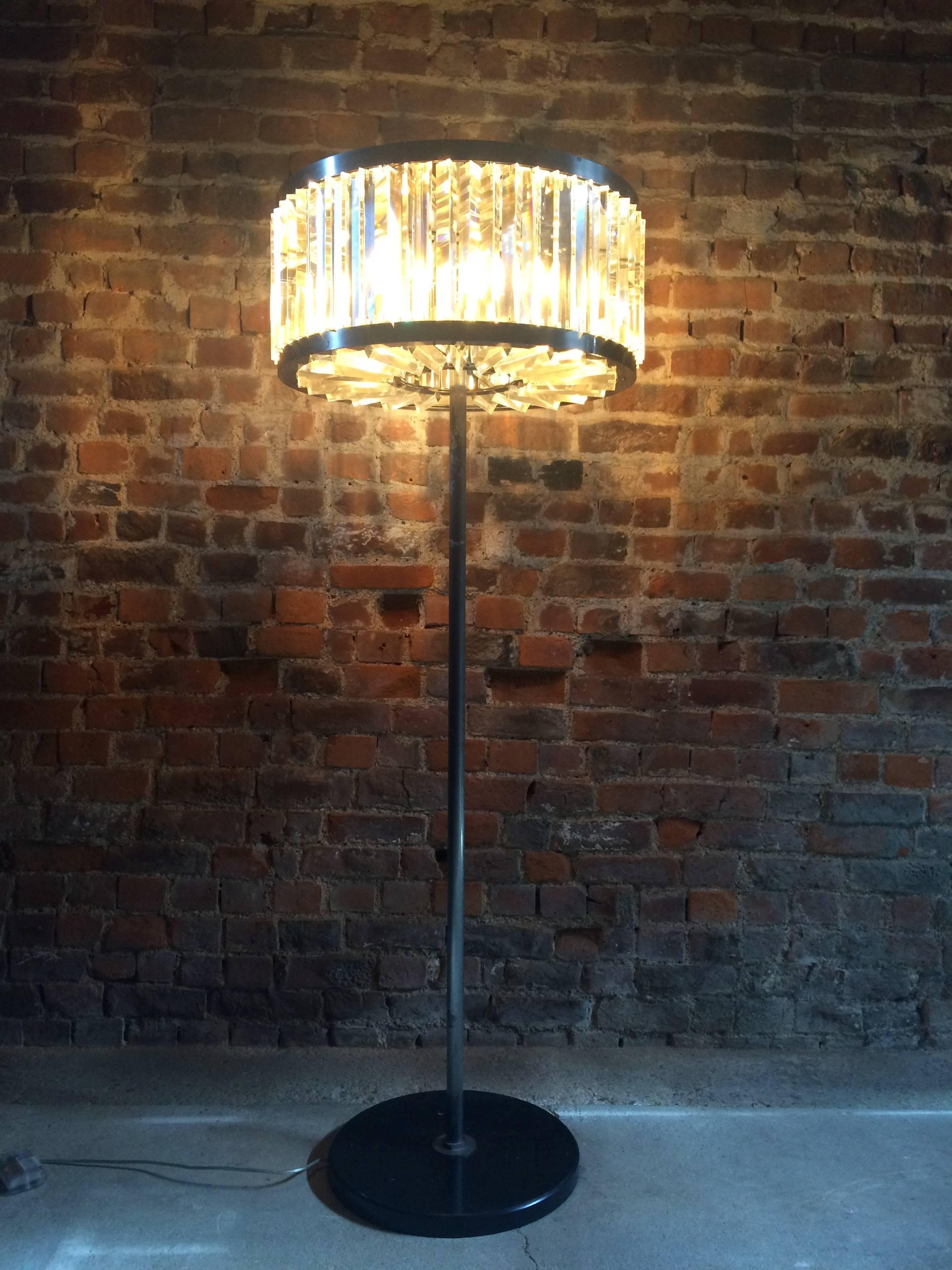 Timothy Oulton takes inspiration for his Rex floor lamp from the historic Rex Cinema, circa 1930s, England. This captivating luminary has an Art Deco aesthetic brought current with contemporary nuances. Its ‘shade’ is handcrafted from prismatic