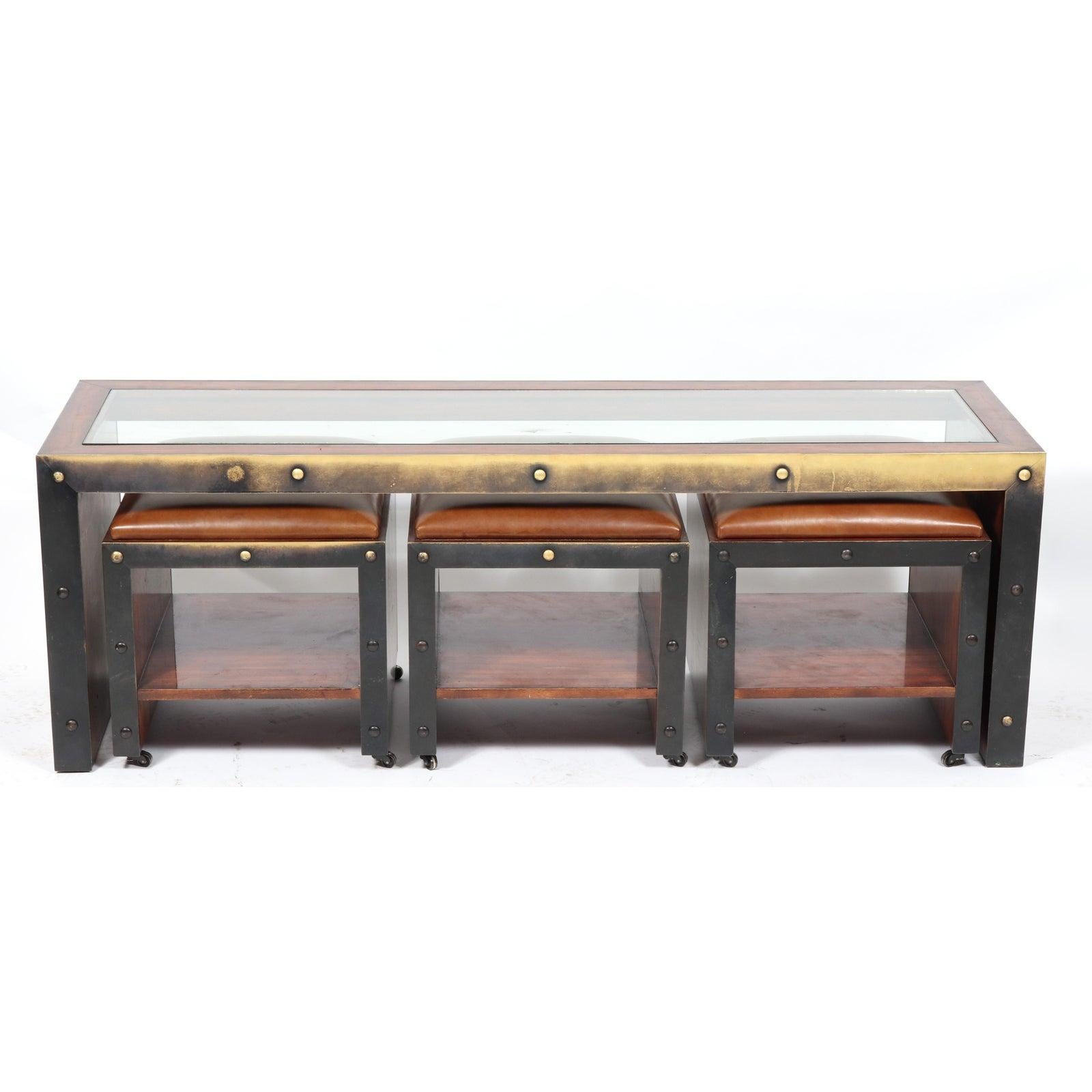 Timothy Oulton industrial style brass mounted coffee table centered with glass top and three leather upholstered ottomans or stools. Features stud detail throughout. 
Table measures 21.5
