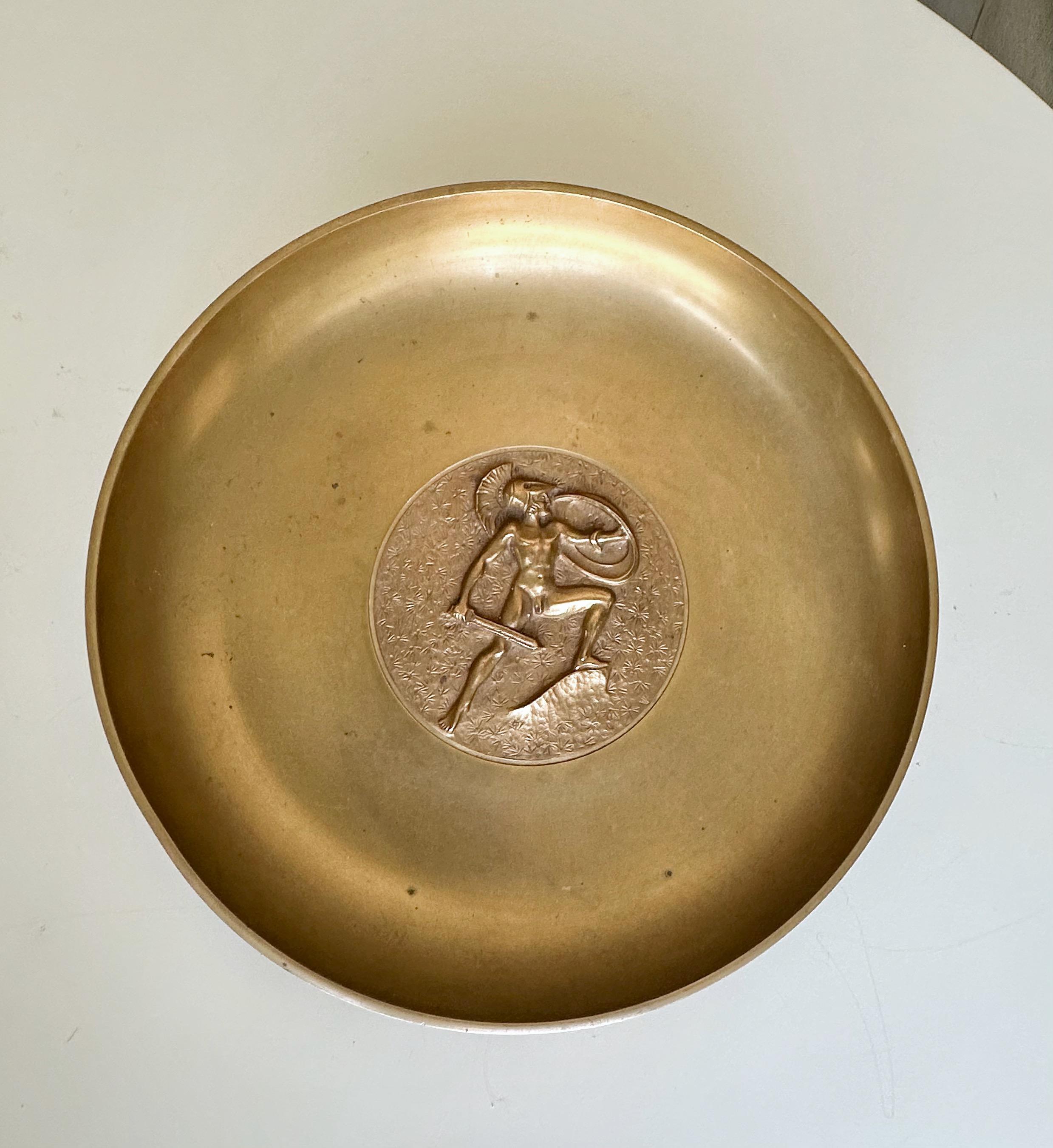 Große, schwere Bronzeschale oder -tablett aus der Deco-Zeit mit der seltenen Darstellung eines neoklassischen männlichen Aktes mit Schwert und Schild, von Tinos aus Dänemark. Signiert auf der Rückseite mit angebrachtem Wandaufhänger.  
