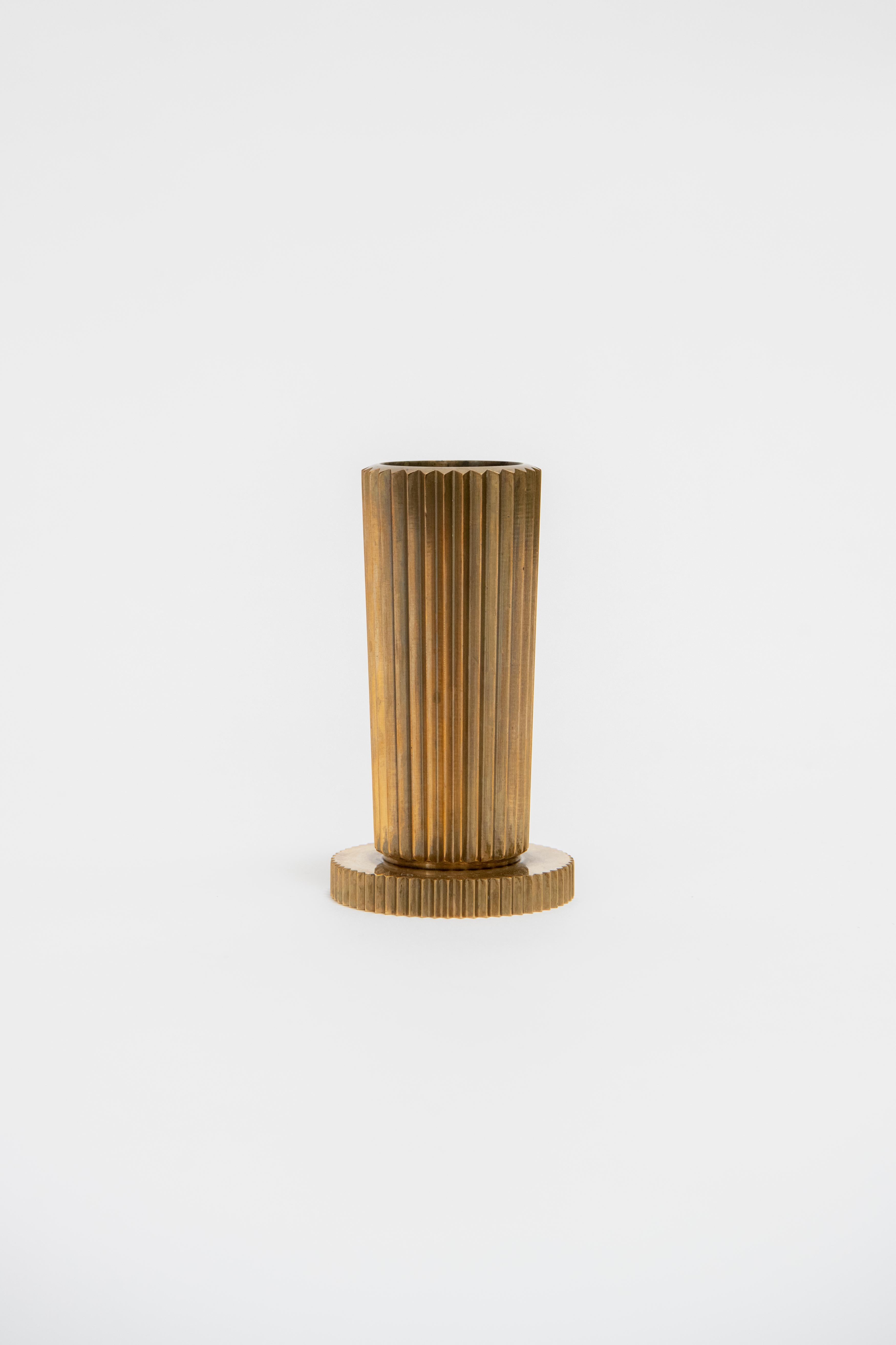 A heavy, solid bronze vase with fluted edges in a machinist style, also reminiscent of an ancient Greek ionic column. Produced by Tinos Bronce Denmark circa 1940. Marked “Tinos Bronce
