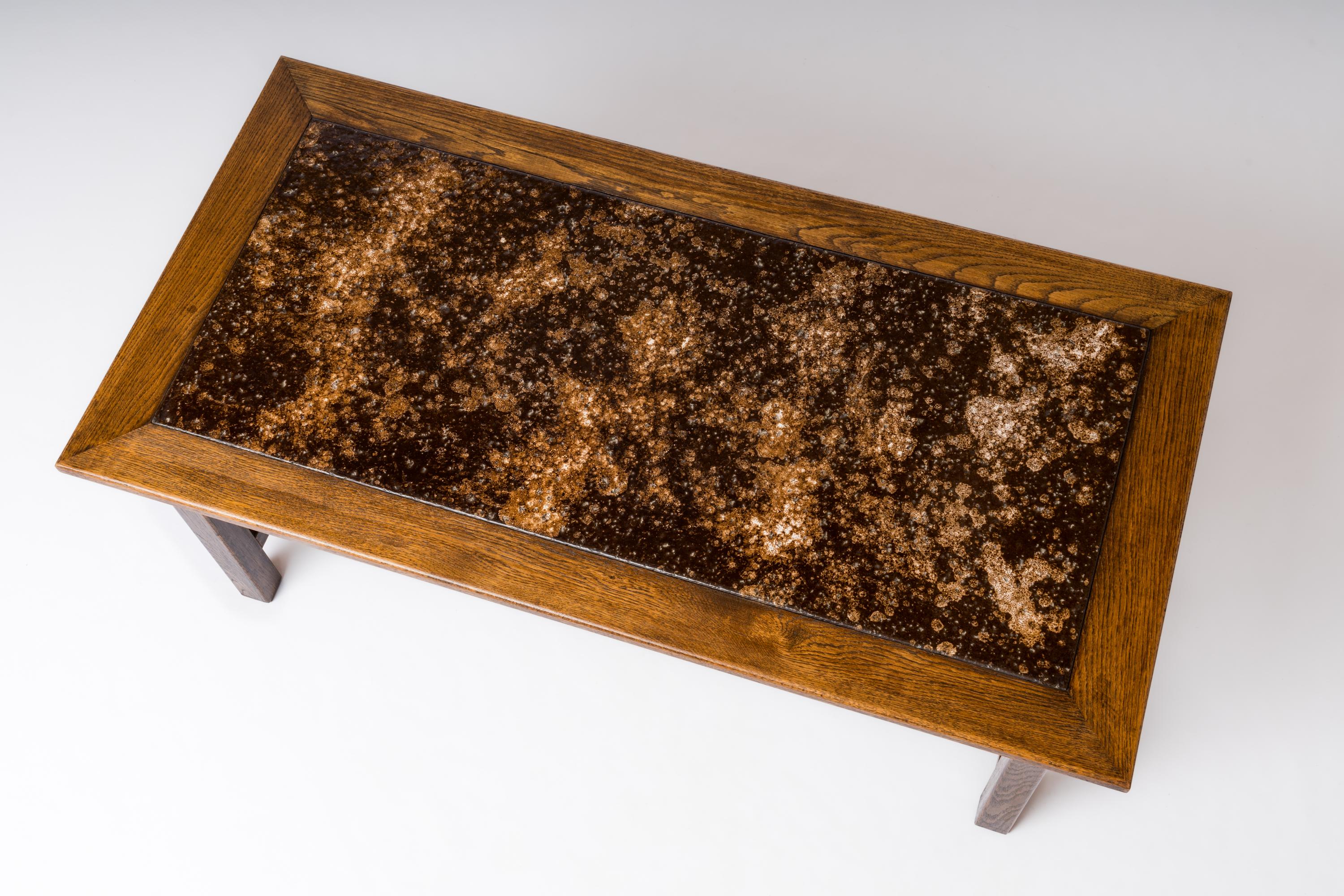 Table basse graphique en chêne foncé et plateau en pierre de lave émaillée avec une structure entretoise. Assemblage par tenon mortaise. Décor unique de laque d'ambre marron et beige sur lave. Une pièce unique. En bon état vintage.
Cette table est