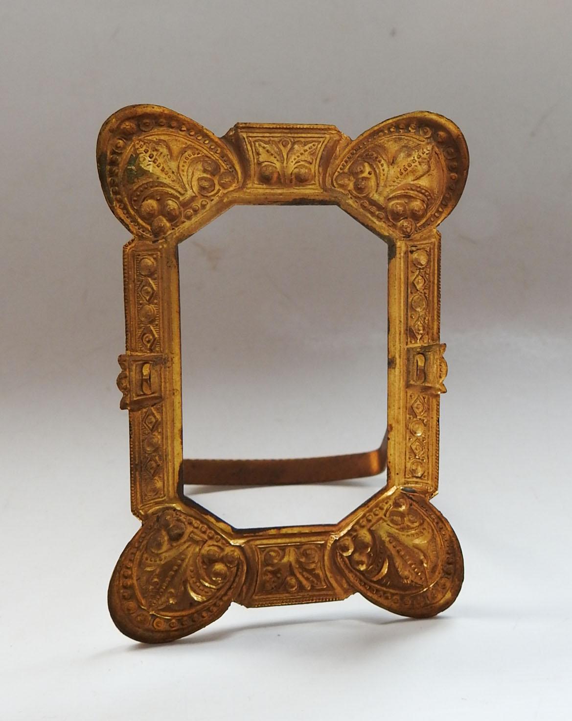 Tiny antique tabletop pressed brass picture frame. With a fleur de lis design, back stand and opening of 1.5