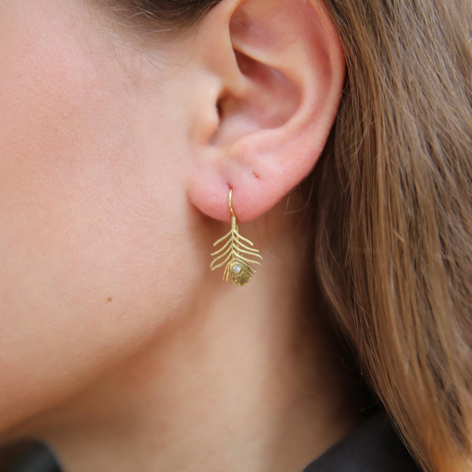 A mini version of our beloved peacock feather design!

These sweet earrings feature a pair of 18k gold peacock feathers with a single tube set diamond. You can almost see them flutter in the breeze! Earrings measure from ear 1
