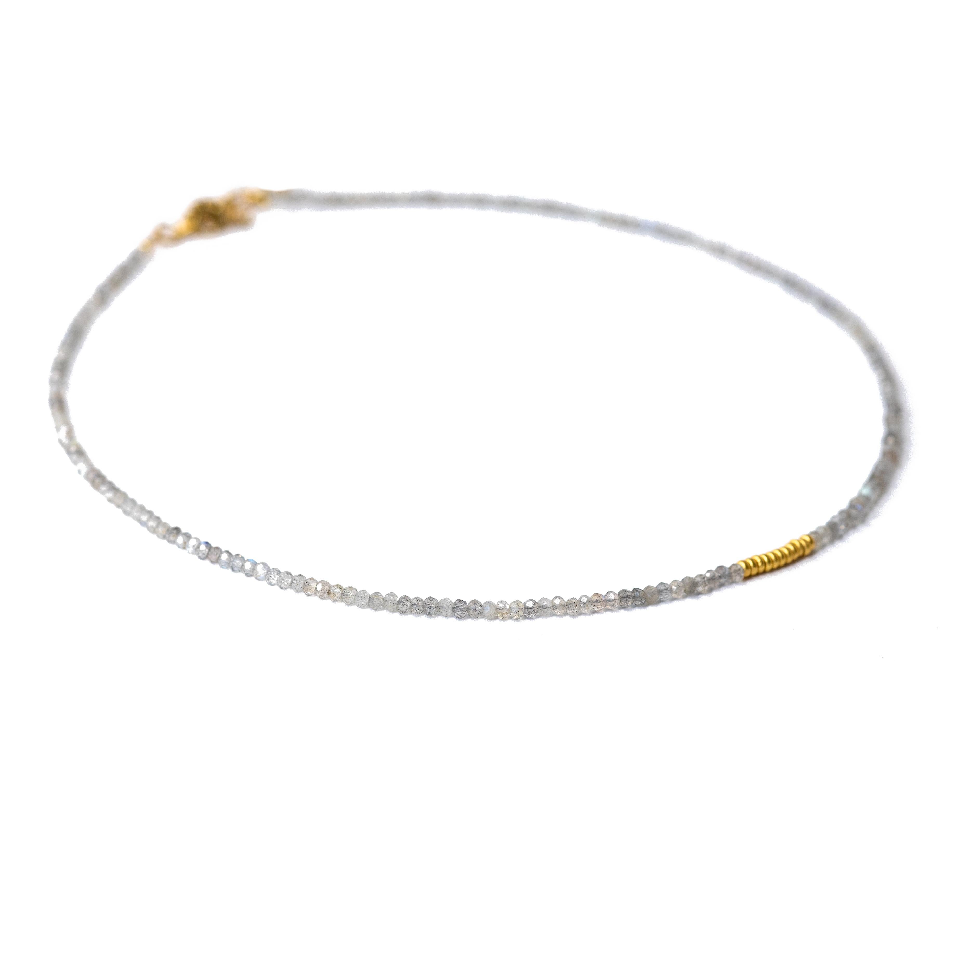 Ce délicat collier de perles d'or en labradorite minuscule est un ajout parfait à toute collection de bijoux. Le tour de cou Shiny Grey est fabriqué avec des perles dorées de haute qualité et comporte une superbe pierre de labradorite qui ajoute une