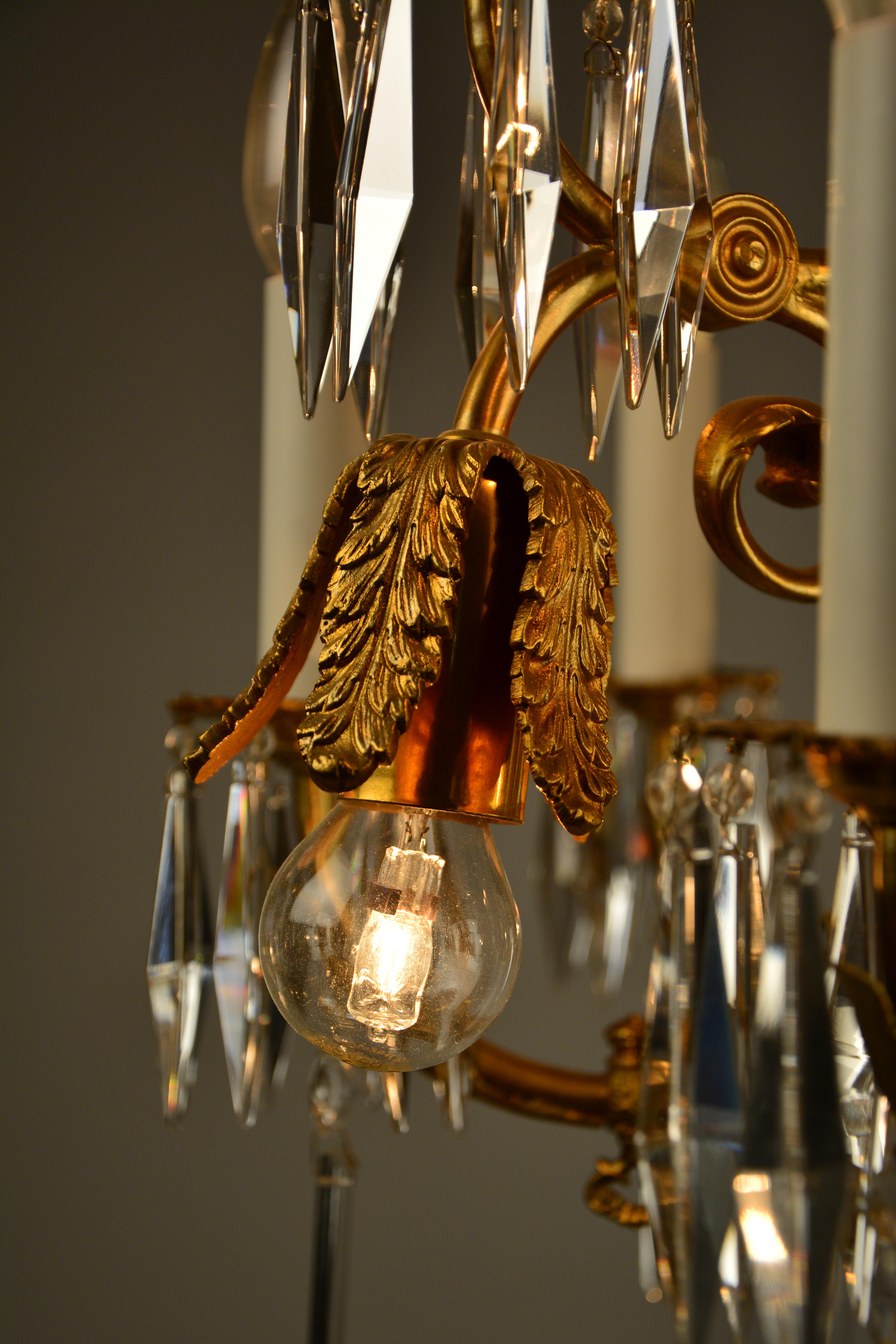 This chandelier from circa 1880-1890 is a former gas light chandelier in the style of Lobmeyr's typical style of the late 19th century. It has 6 plus 3 candle lights and 3 downward lights under a cast brass leaf design. The item still has the