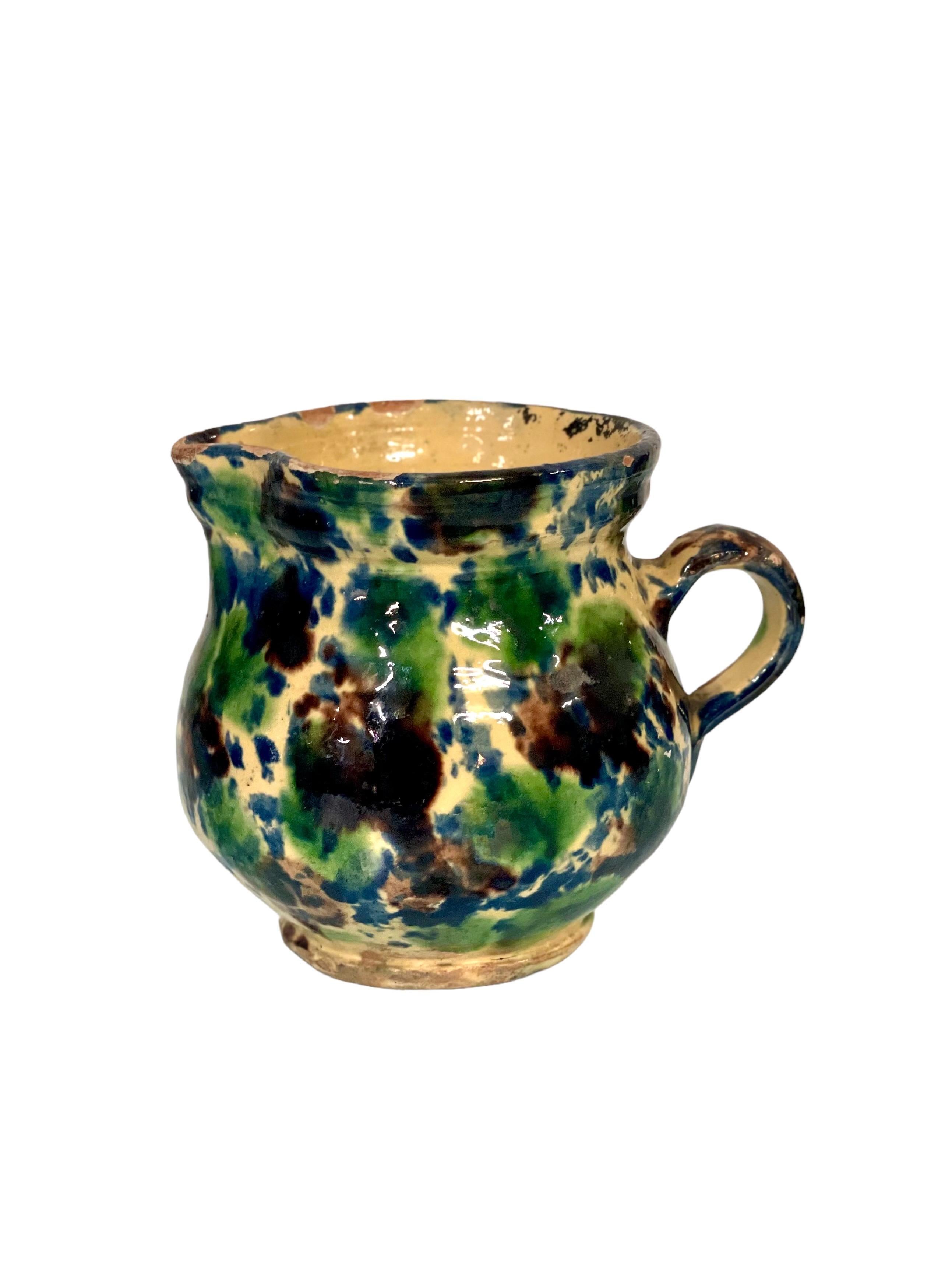 A tiny French rustic terracotta water or milk jug with handle and shaped spout, decorated in an eye-catching multicoloured glaze. Ideal for a country-style home or farmhouse kitchen. 19th century.