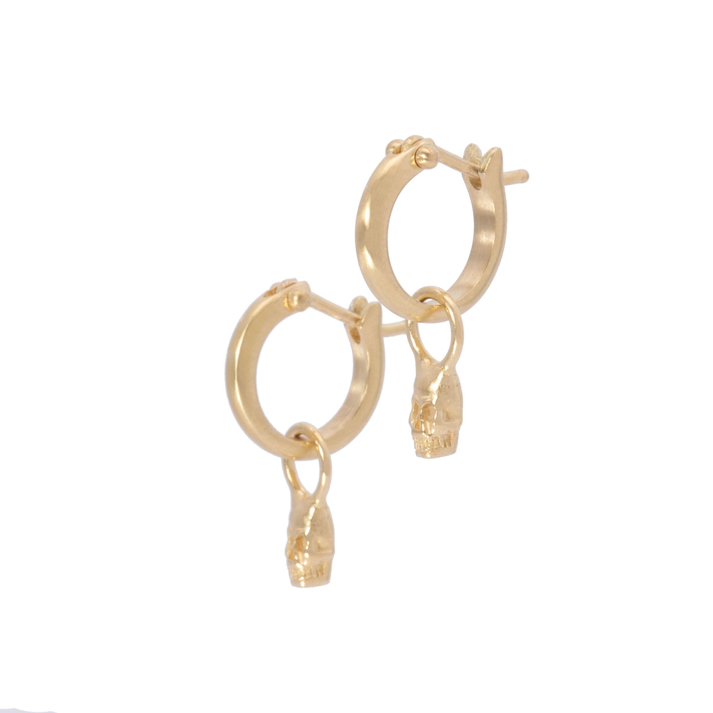 Tiny skulls hand crafted in 18k gold grin beneath small plain hoop earrings which click shut for security. As the symbol for both the past and the future, our ancestors and life, these tiny skull drop earrings in 18k gold are a whimsical nod to the