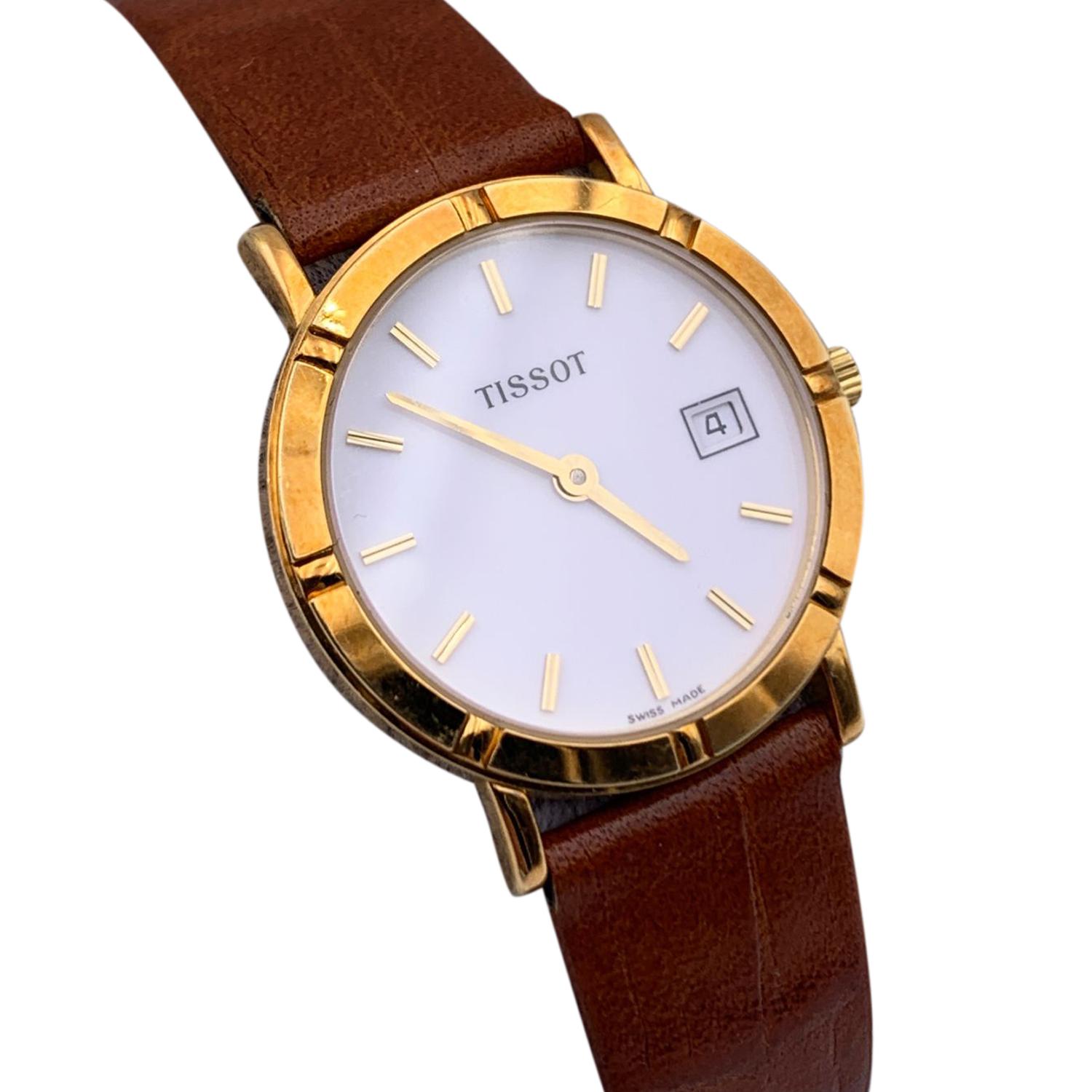 Beautiful vintage wristwatch by Tissot. Round 18k yellow gold case. White tone dial. Swiss Made Quartz Movement. Brown leather wrist strap with 7 holes adjustment. Date indicator at 3 o'clock. 'Tissot' lettering on the dial. otal length: 8.25 inches