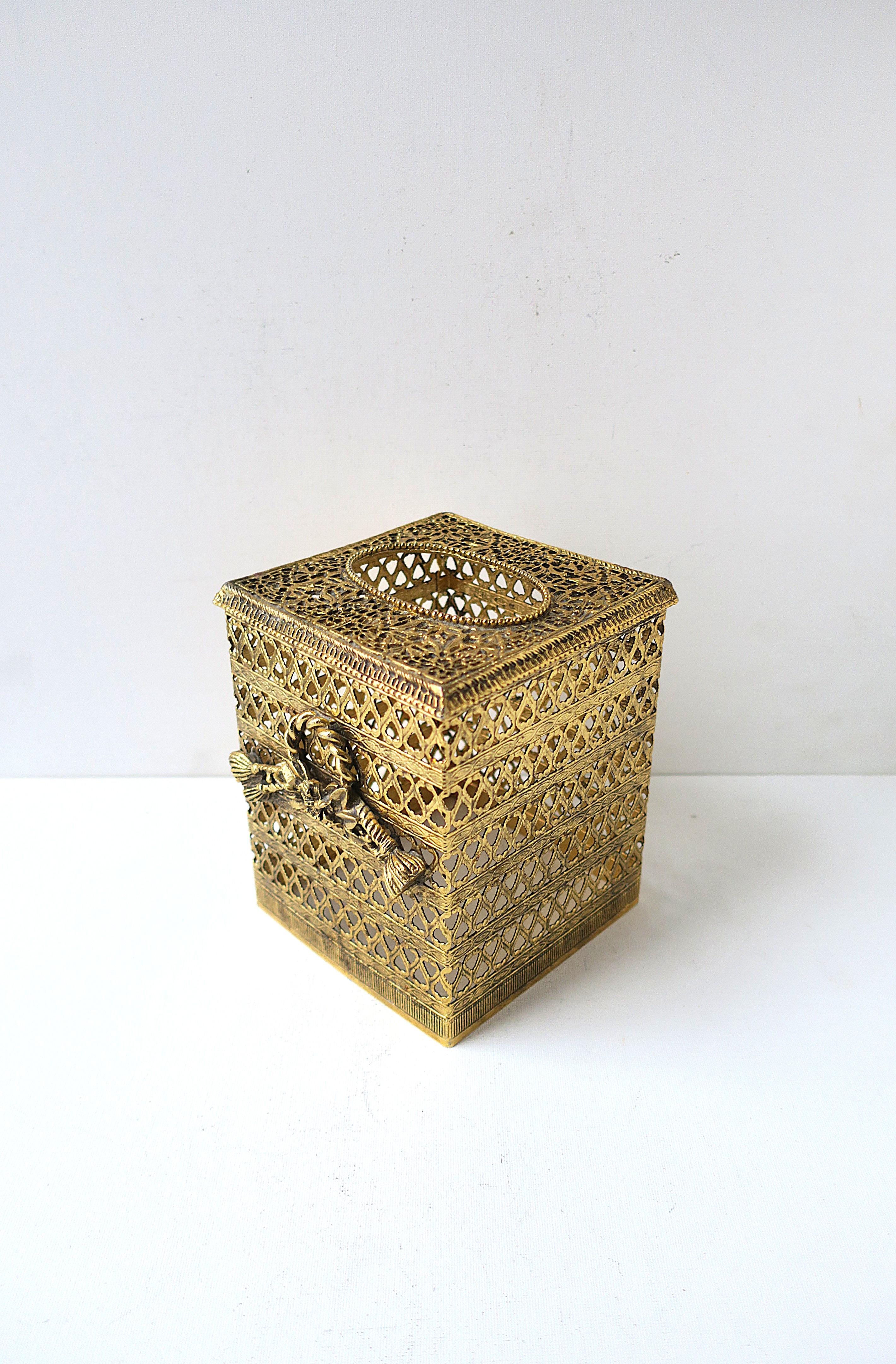Coperchio per scatola di fazzoletti in metallo placcato in ottone con disegno di corda e nappe, circa metà del XX secolo, anni '60. Il pezzo è di un vivace color oro con una corda attorcigliata e un dettaglio di nappe sul davanti. È un'ottima