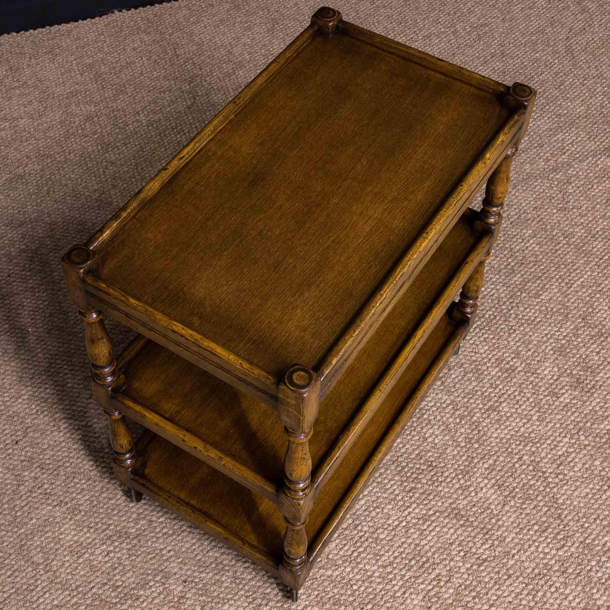 An excellent quality oak tea trolley with a slightly distressed finish similar to that of the well known Ipswich firm Titchmarsh and Goodwin. The original brass wheels are all in good working order and running smoothly.