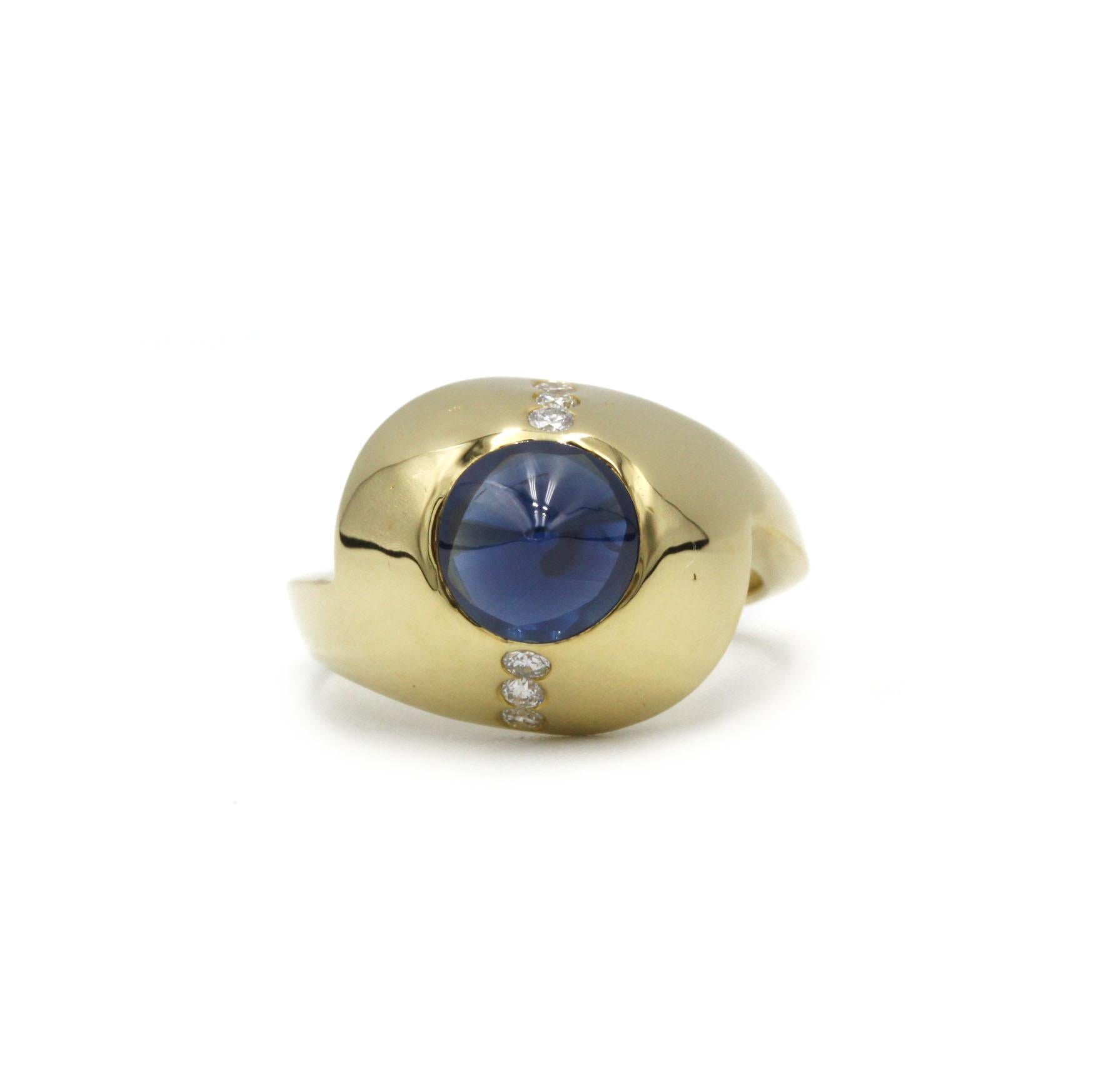 Audace anello anni '70 realizzato in oro giallo 18 carati, con al centro un sorprendente zaffiro blu a forma di cono che cattura la luce con una tonalità profonda e luminosa. Lo zaffiro è incastonato a filo all'interno di una cupola d'oro liscia e