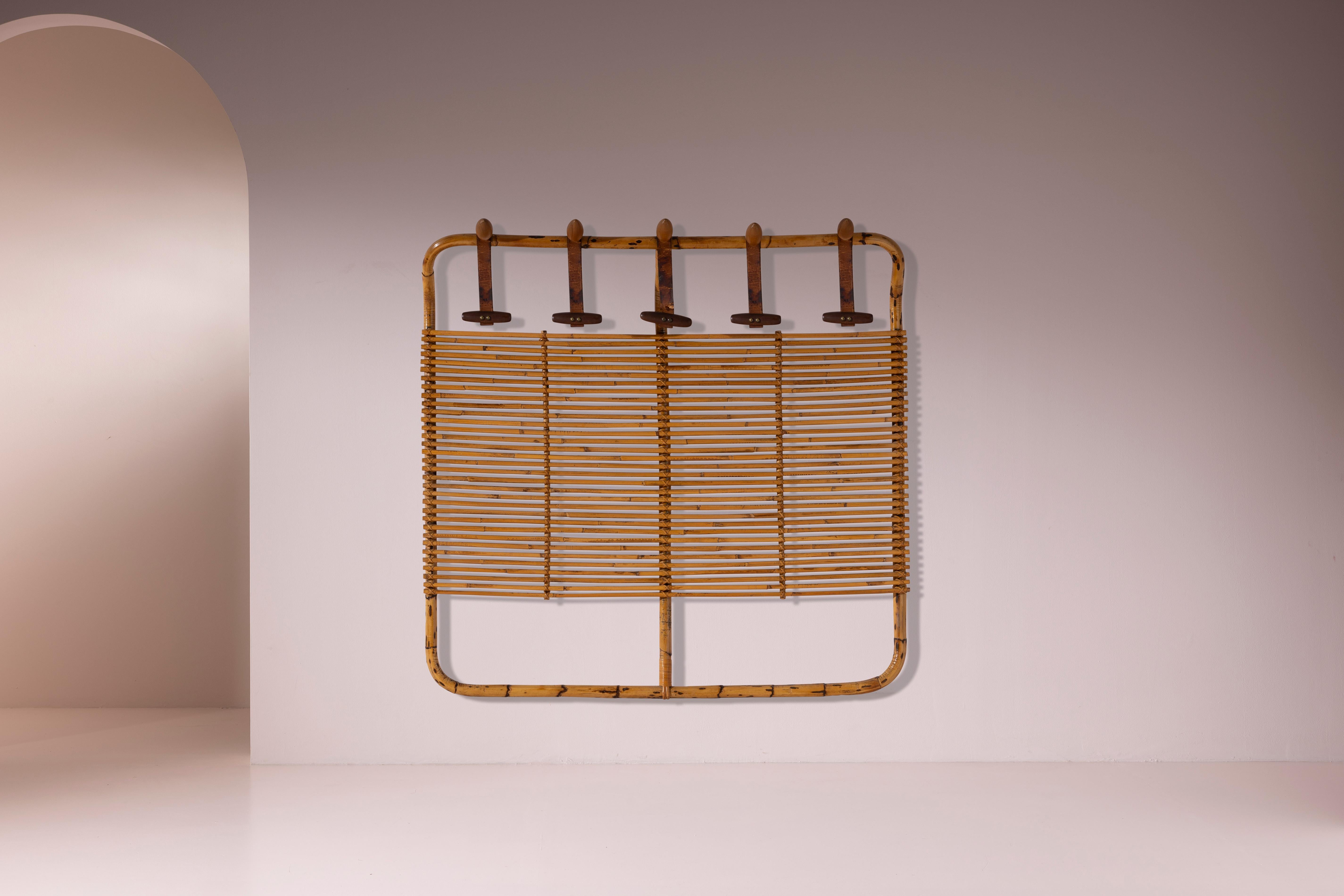 Este perchero de ratán, diseñado por Tito Agnoli para Bonacina a principios de la década de 1960, revela la serena precisión de la artesanía italiana de la época. La estructura combina elementos curvos de ratán y bambú con finas ligaduras que dan
