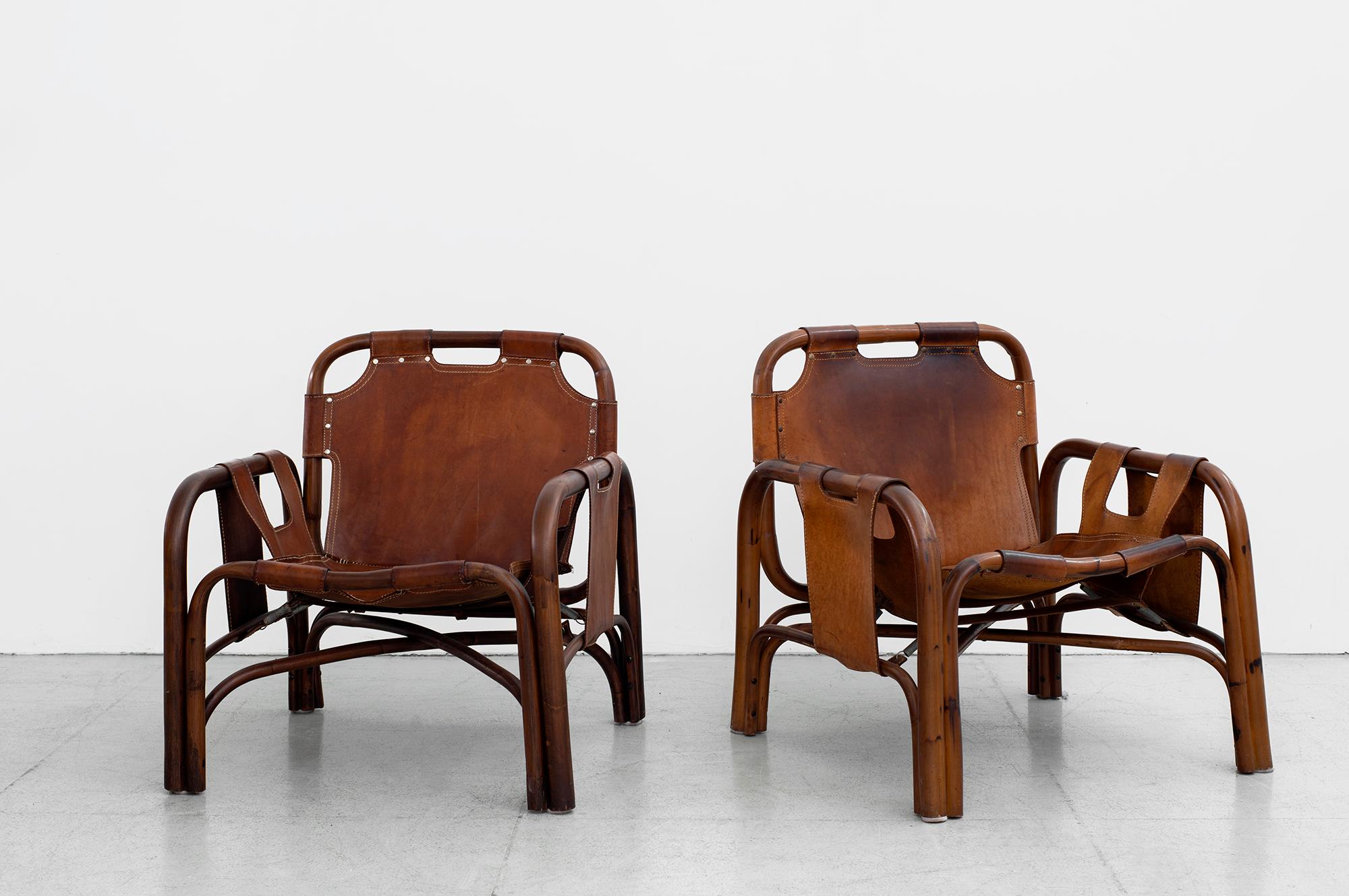 Leather sling lounge chairs by Tito Agnoli for Bonacina with bamboo frames, wonderful patina'd leather and rivets. 
 