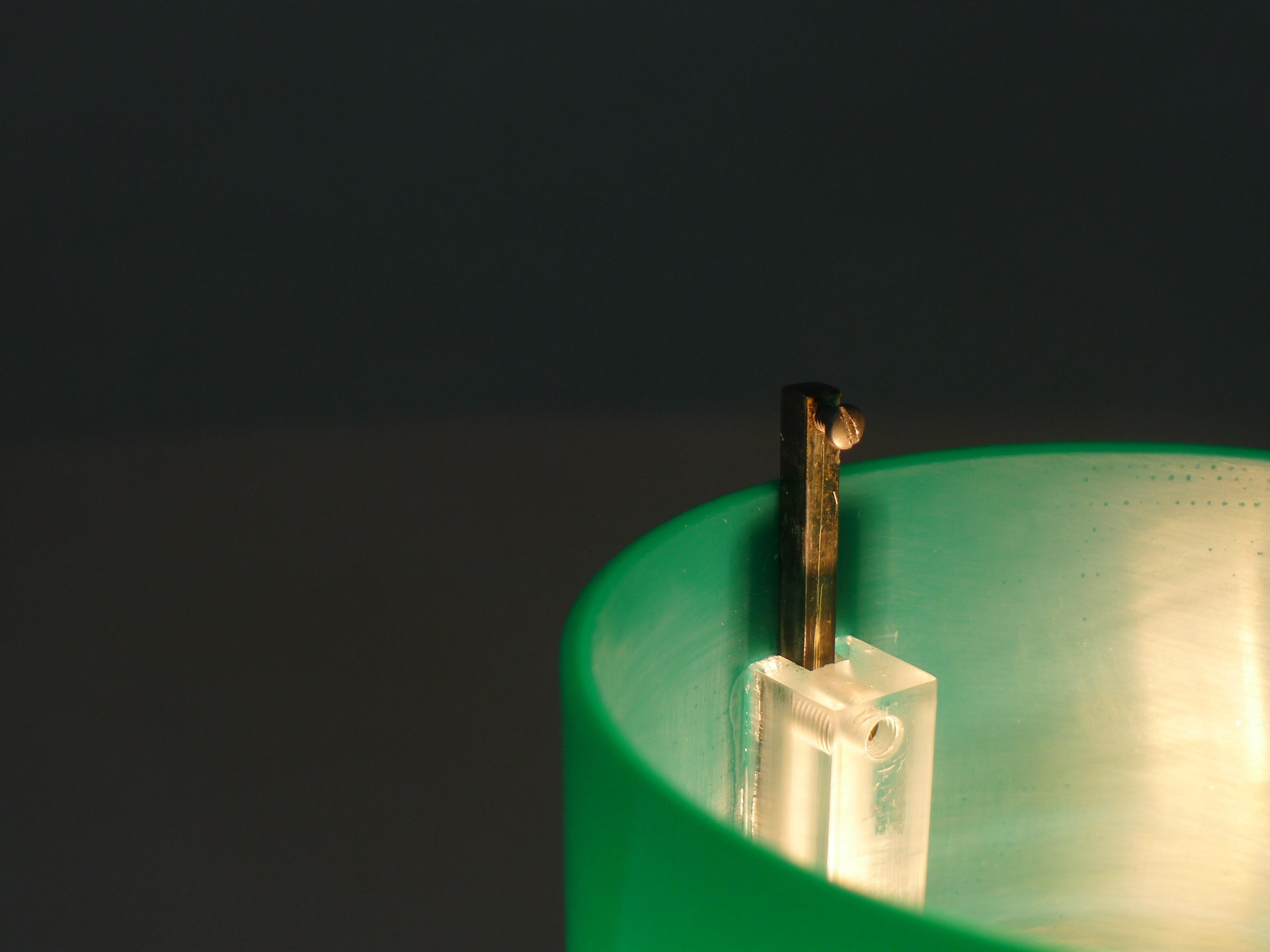 Tito Agnoli, lampada da tavolo o da scrivania, modello 269 per Oluce, Italia. Un cilindro rifinito in nichel sostiene un pilastro verticale con denti dentati che permettono al paralume in perspex verde di salire e scendere di circa 3 cm dall'alto