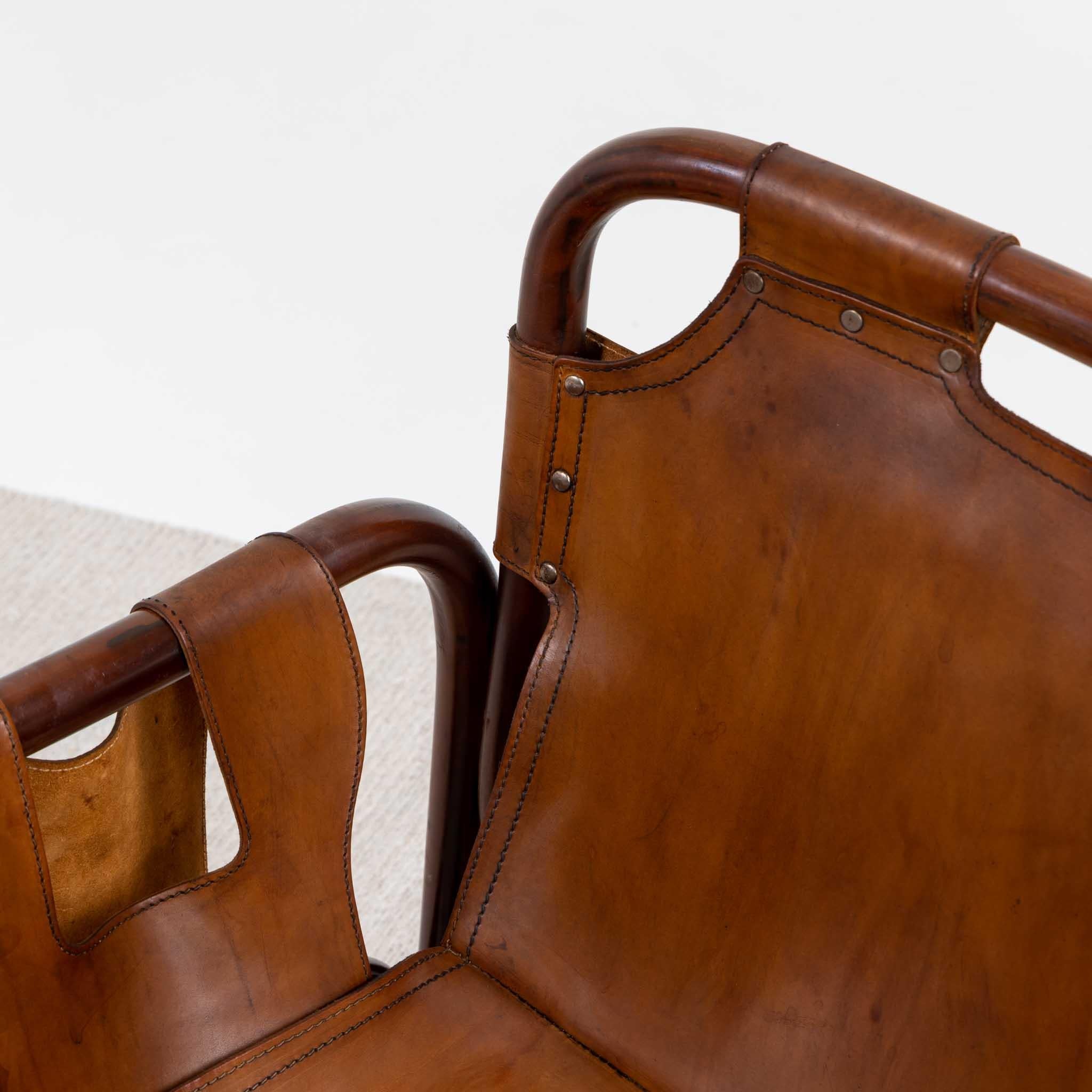 Pair of armchairs with dark stained bamboo frames and brown smooth leather upholstery.