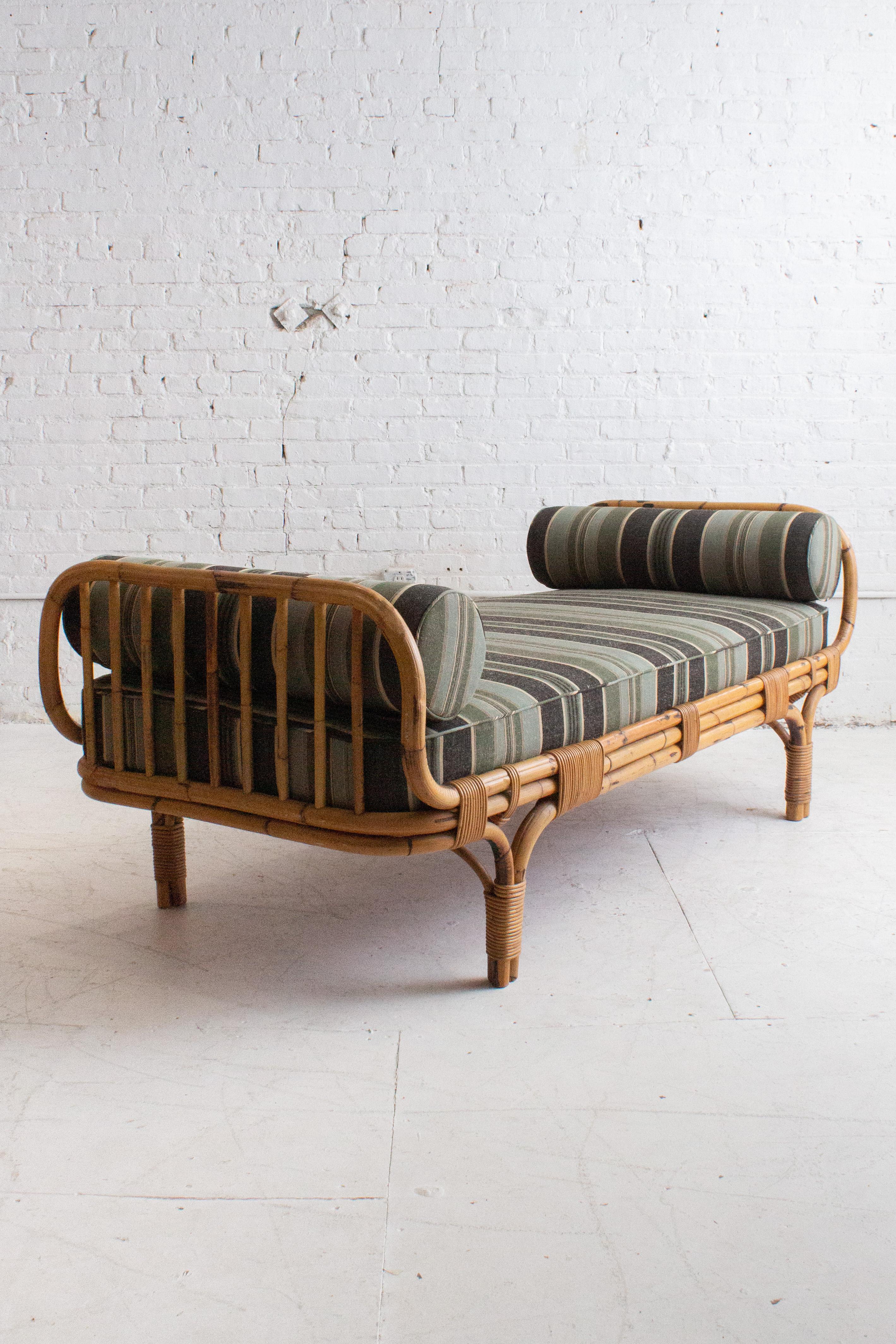 A mid century Italian rattan daybed attributed to Tito Agnoli for Bonacina. Newly upholstered with new foam and a striped wool blend fabric complete with matching bolster pillows. Sourced in Northern Italy.

Tito Agnoli (1931–2023) was an