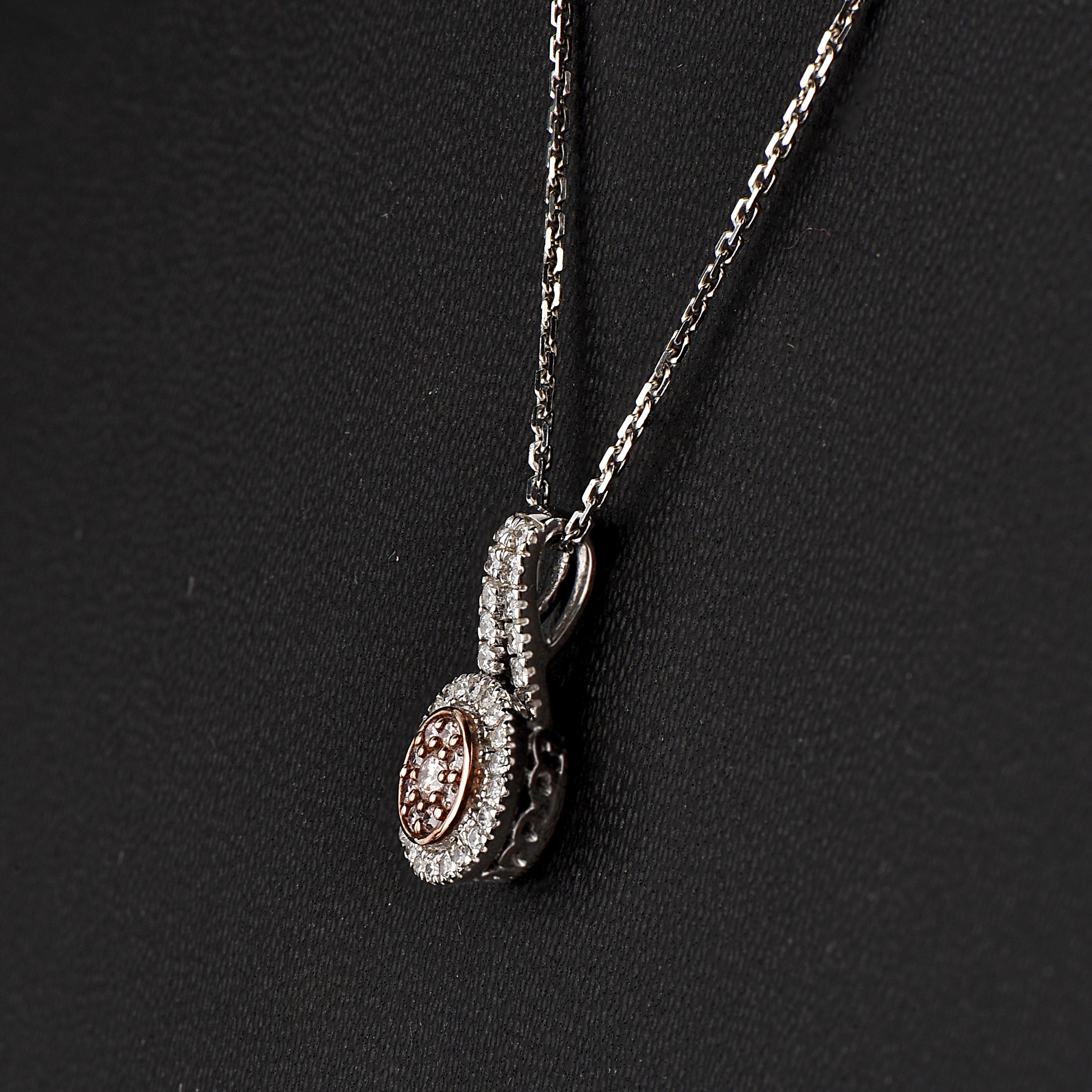 Dai un tocco di fascino al tuo look con questo ciondolo con cornice di diamanti. Il pendente è realizzato in oro bianco da 18 carati e presenta 31 diamanti bianchi e 9 diamanti rosa a brillante rotondo, incastonati a micropunte e a griffe, di colore