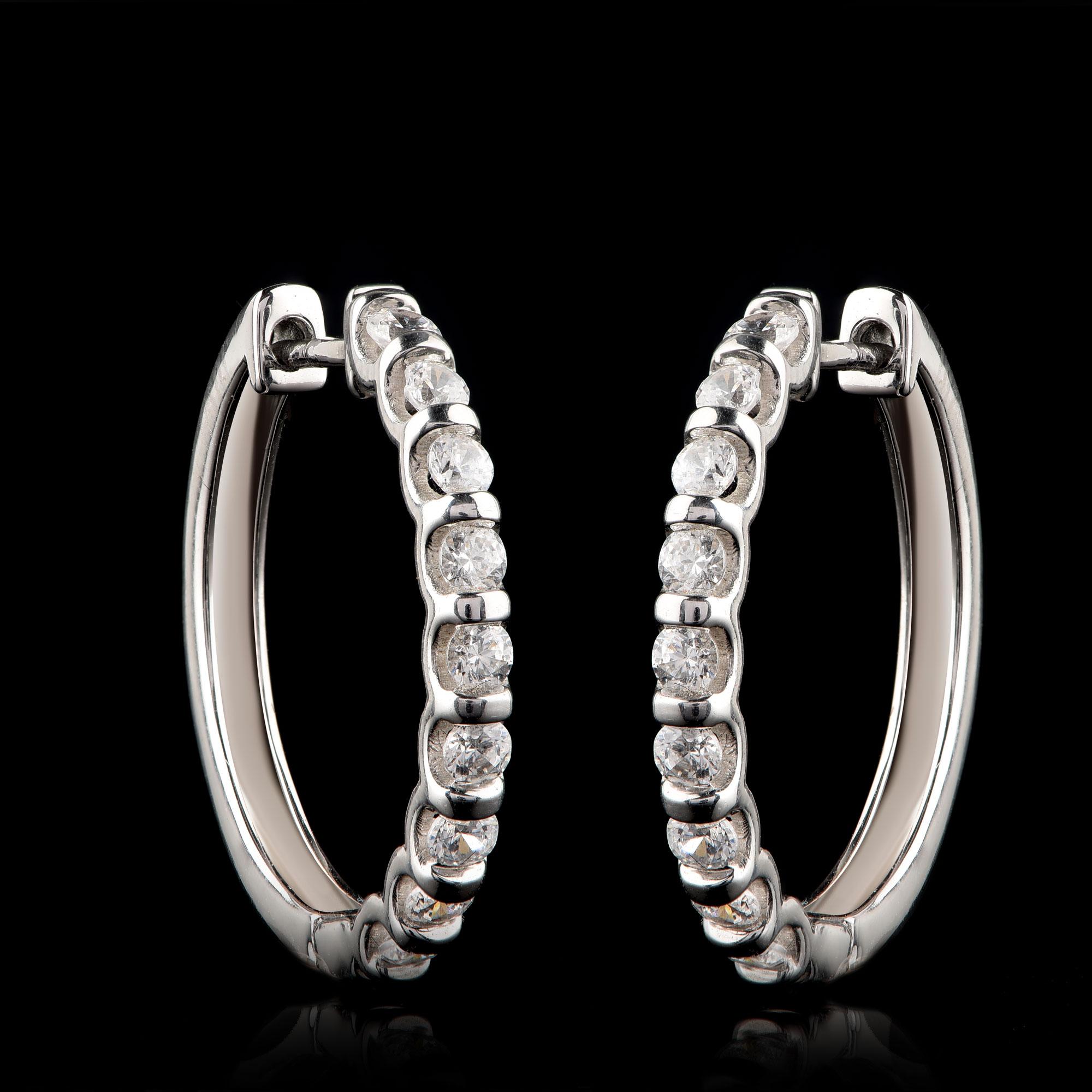 These classic diamond hoop earrings are expertly hand-crafted in 18-karat white gold and 18 brilliant-cut diamonds studded beautifully in channel setting. The diamonds are graded H-I Color, I2 Clarity.