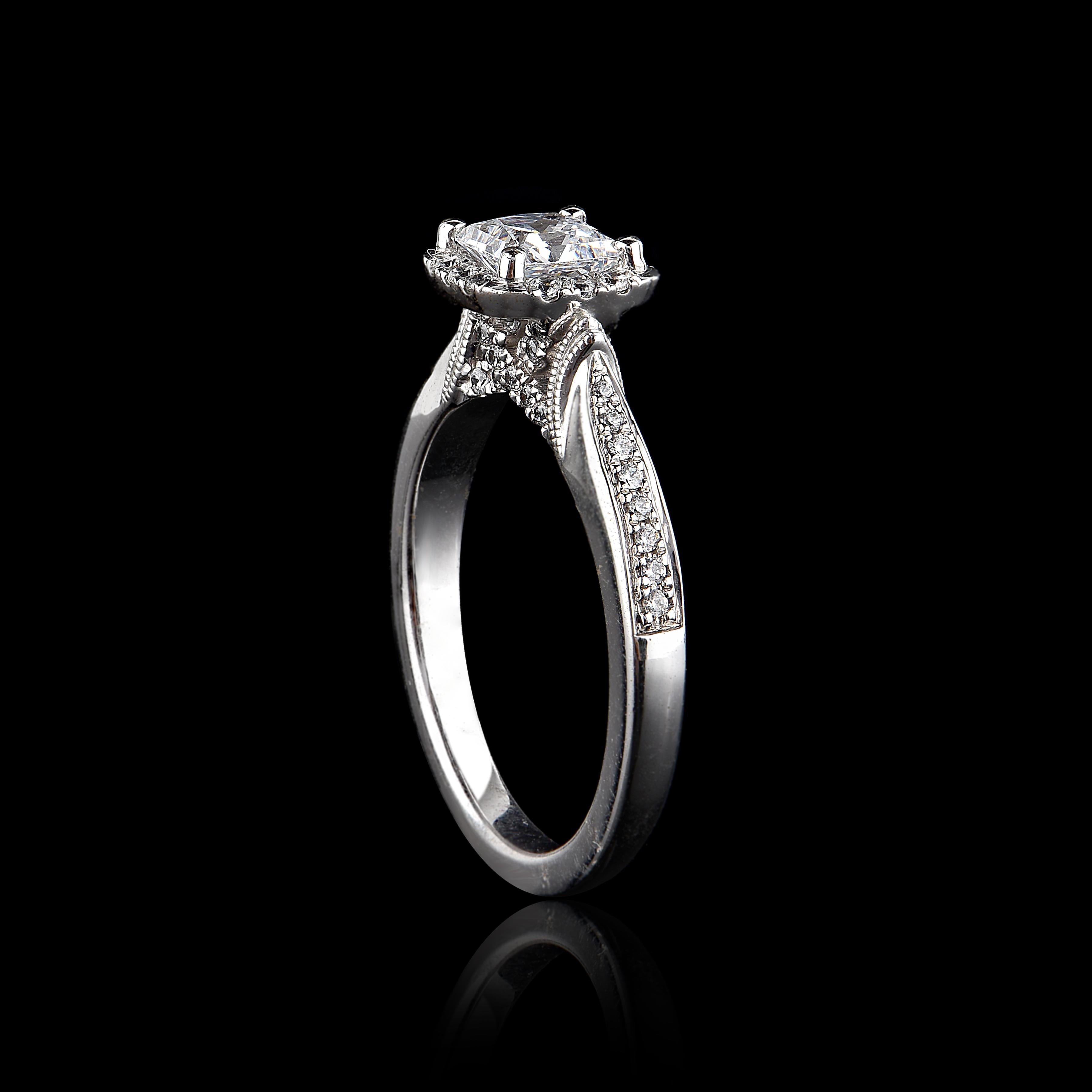 Este anillo de compromiso de diamantes está elaborado por expertos en oro blanco de 18 quilates y cuenta con una piedra central de 0,75 quilates y 0,25 quilates de diamantes alineados en el marco y la caña, engastados con garras. Los diamantes son
