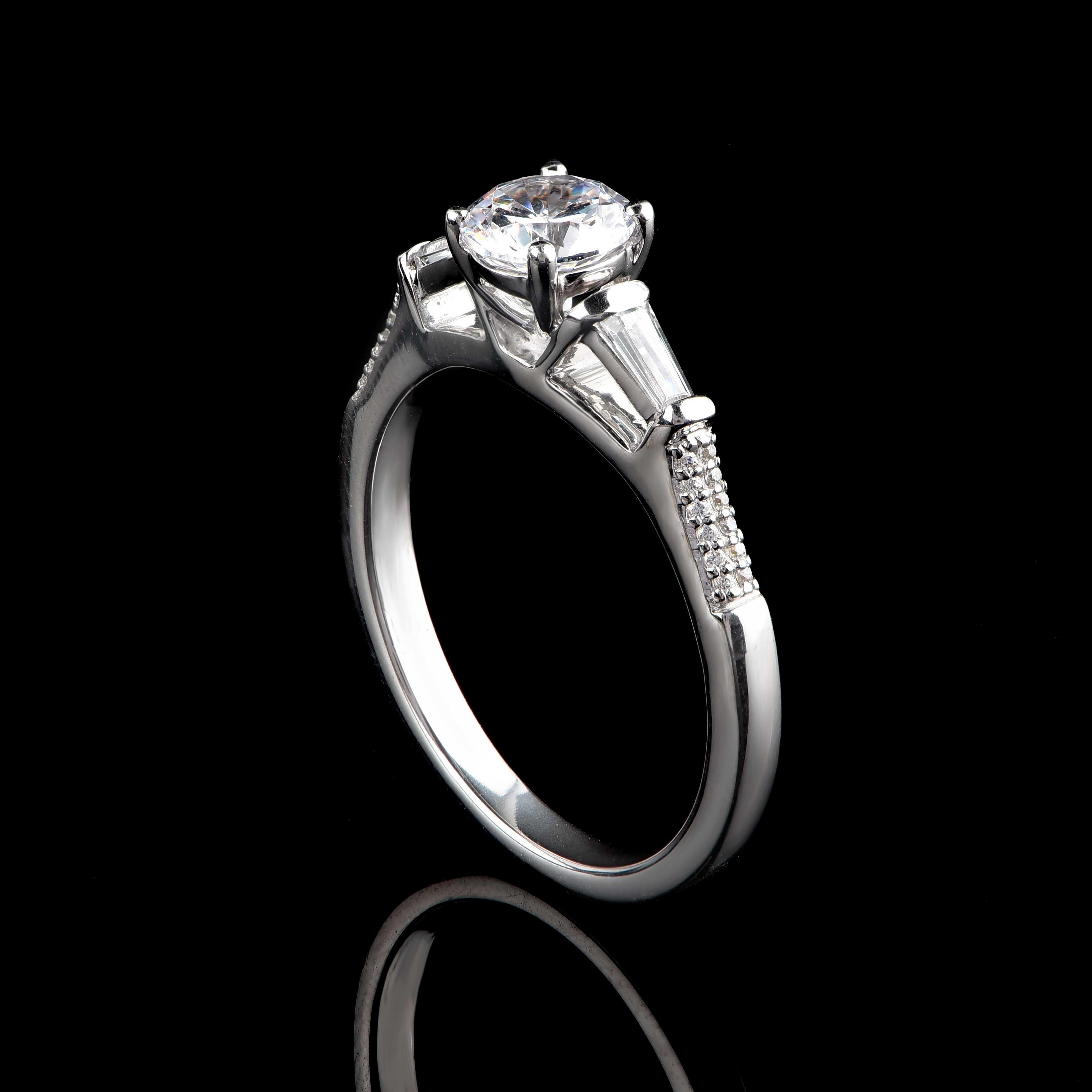 This diamond bridal ring dazzles beautifully with 24 brilliant-cut and 2 baguette-cut diamonds and 1 GIA certified centre stone set beautifully in prong, pave and channel setting - crafted in 18-karat white gold. Diamonds are graded H Color, SI1