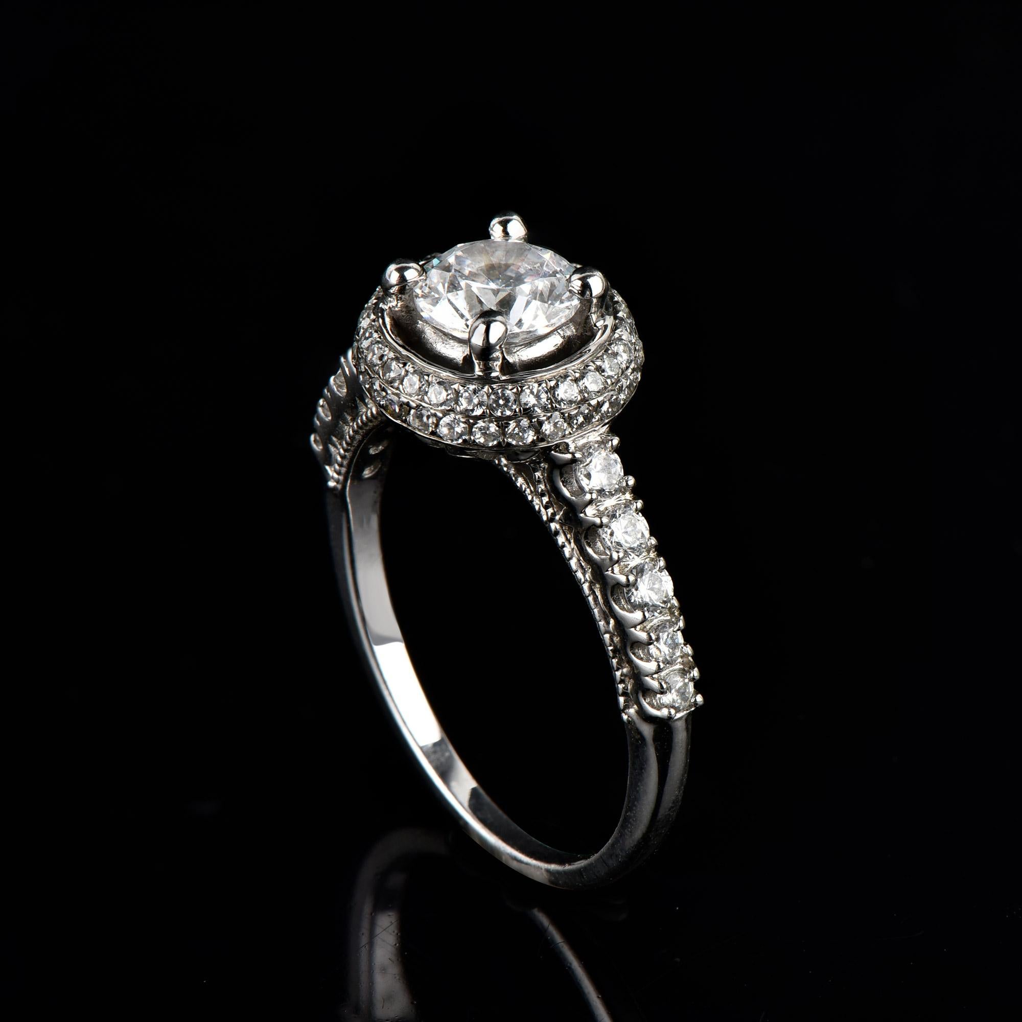 Véritablement exquise, cette bague de fiançailles en diamant ne manquera pas d'être admirée pour la beauté classique et l'élégance inhérentes à son design, qui comprend une pierre centrale de 0,75 ct et une monture en diamant de 0,50 ct, ainsi que