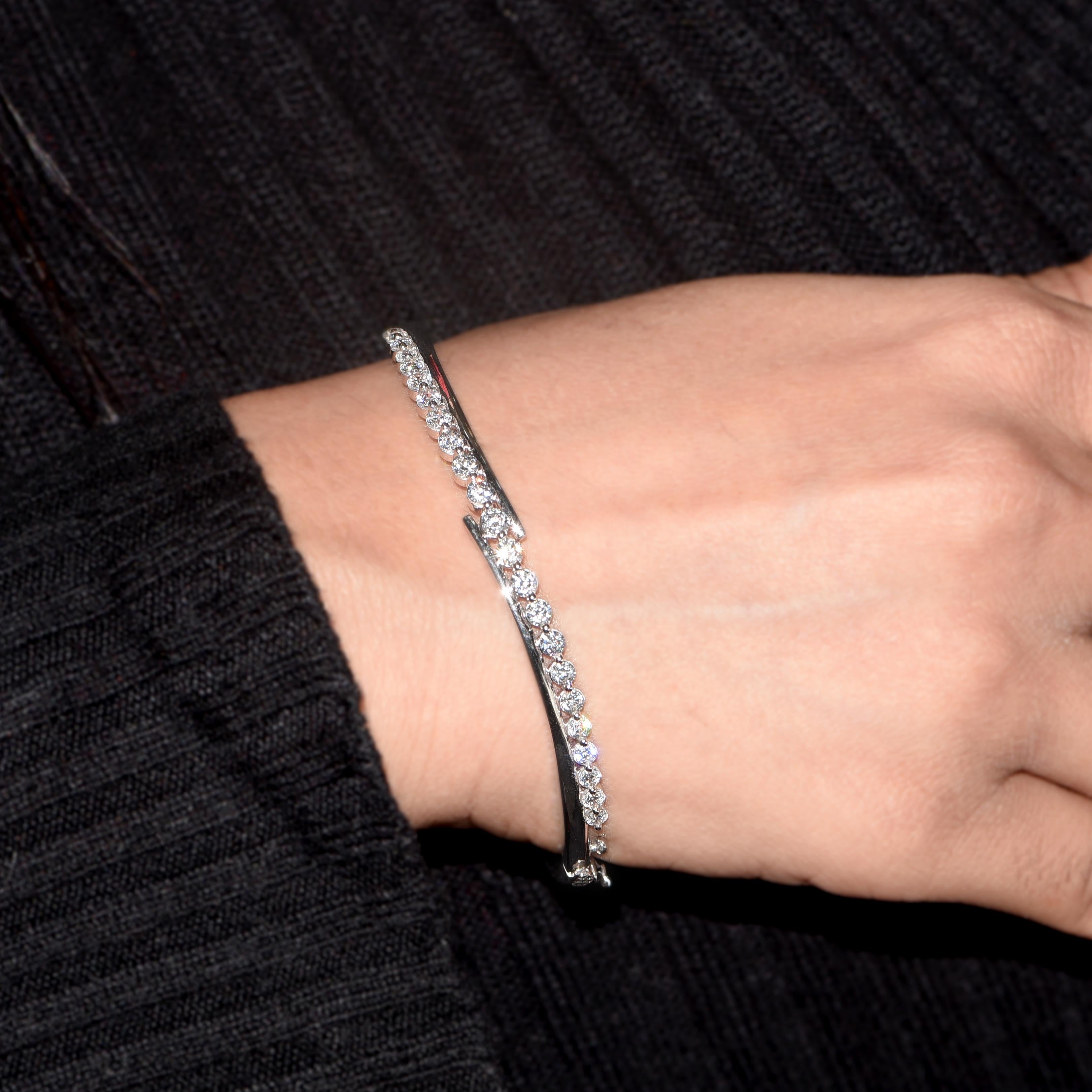 Ce bracelet design en diamant brille de tous ses feux avec ses 23 diamants taille brillant sertis en griffe et réalisés par nos experts en or blanc 18 carats. Les diamants sont classés H-I Color, I2 Clarity. 
Le diamètre de ce bangle est de 62.00 MM