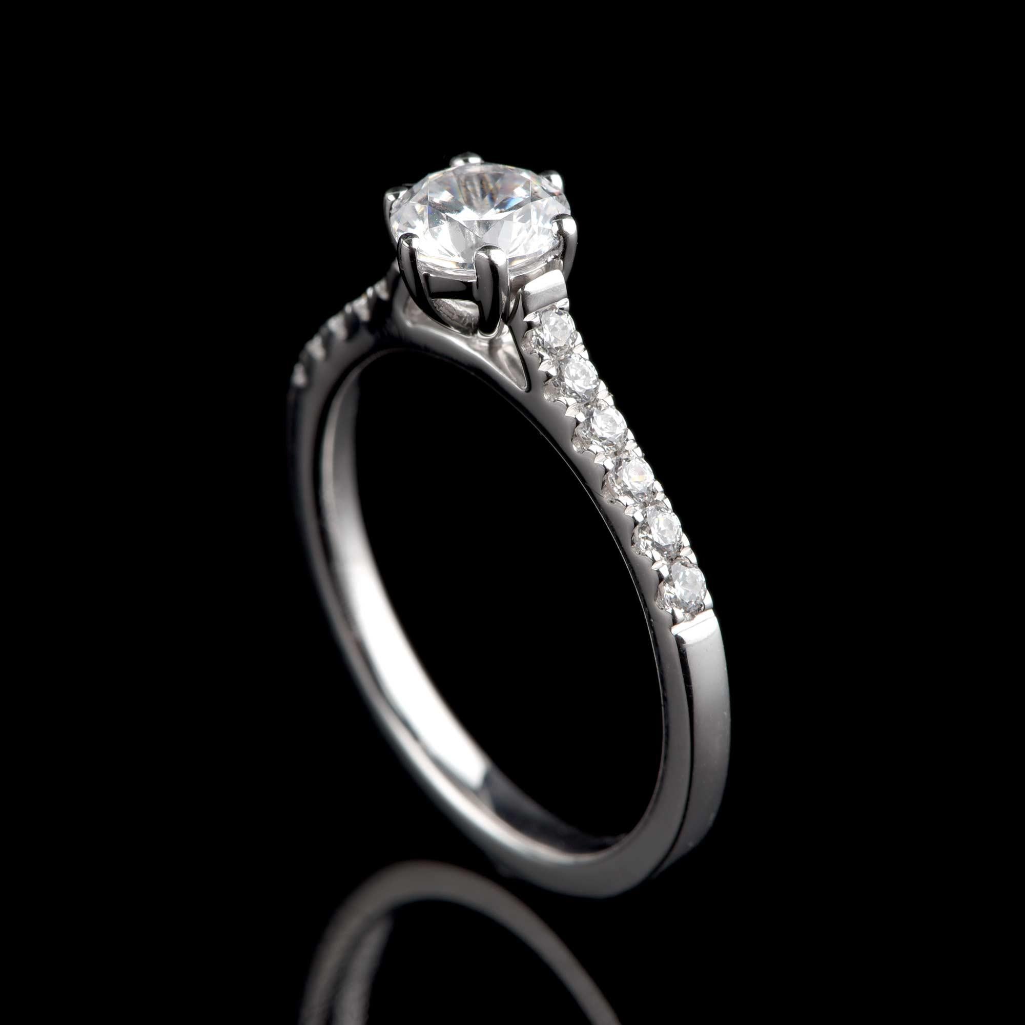 This classic bridal ring features 12 brilliant-cut diamonds and 1 GIA certified centre stone in prong setting and crafted in 18-karat white gold. The diamonds are graded H Color, SI1 Clarity.