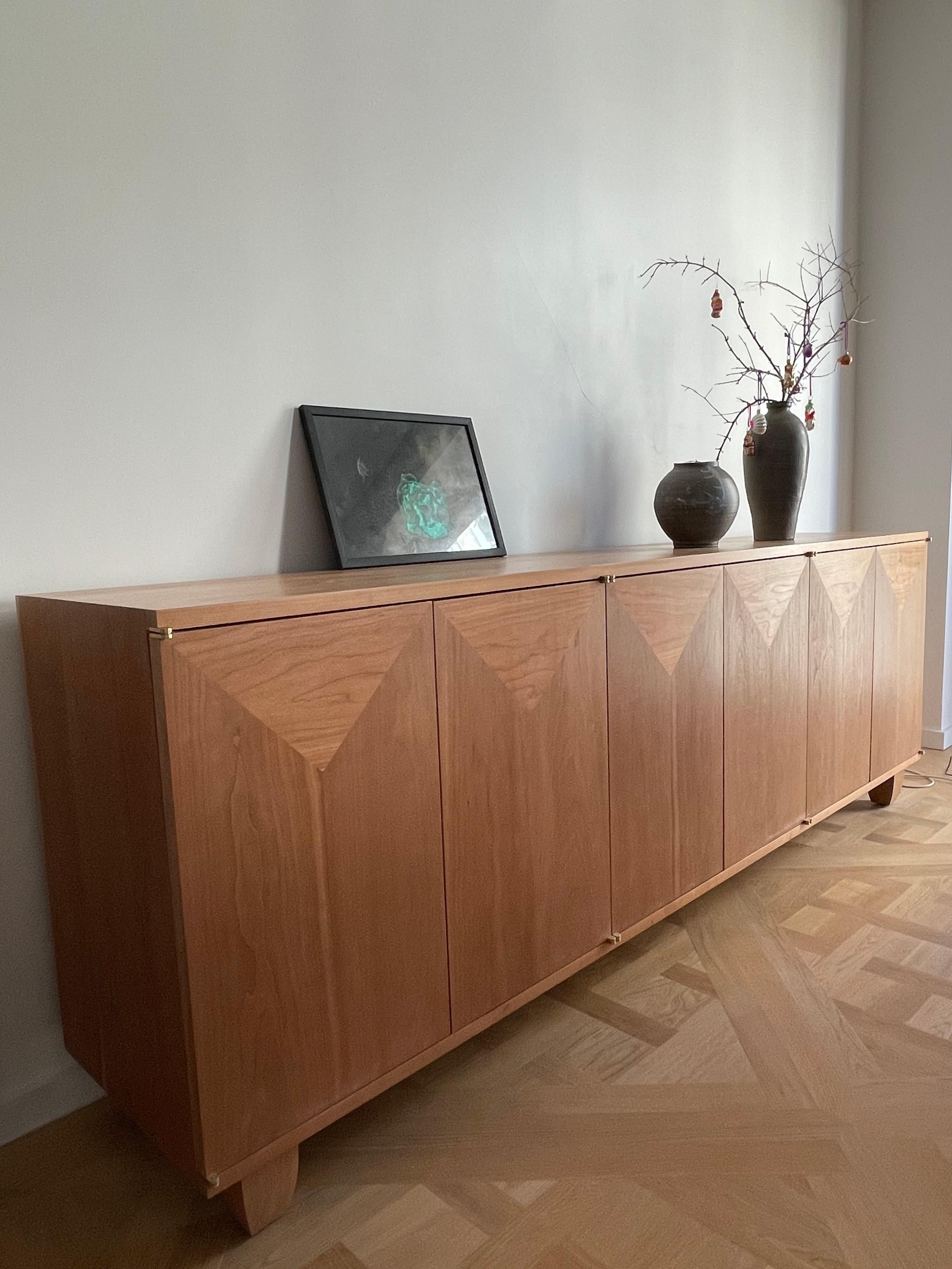 This is a solid North American cherry wood sideboard with custom concealed brass pivot hinges.
The piece was inspired by the designer’s love for the natural beauty and integrity of this indigenous New England wood.
