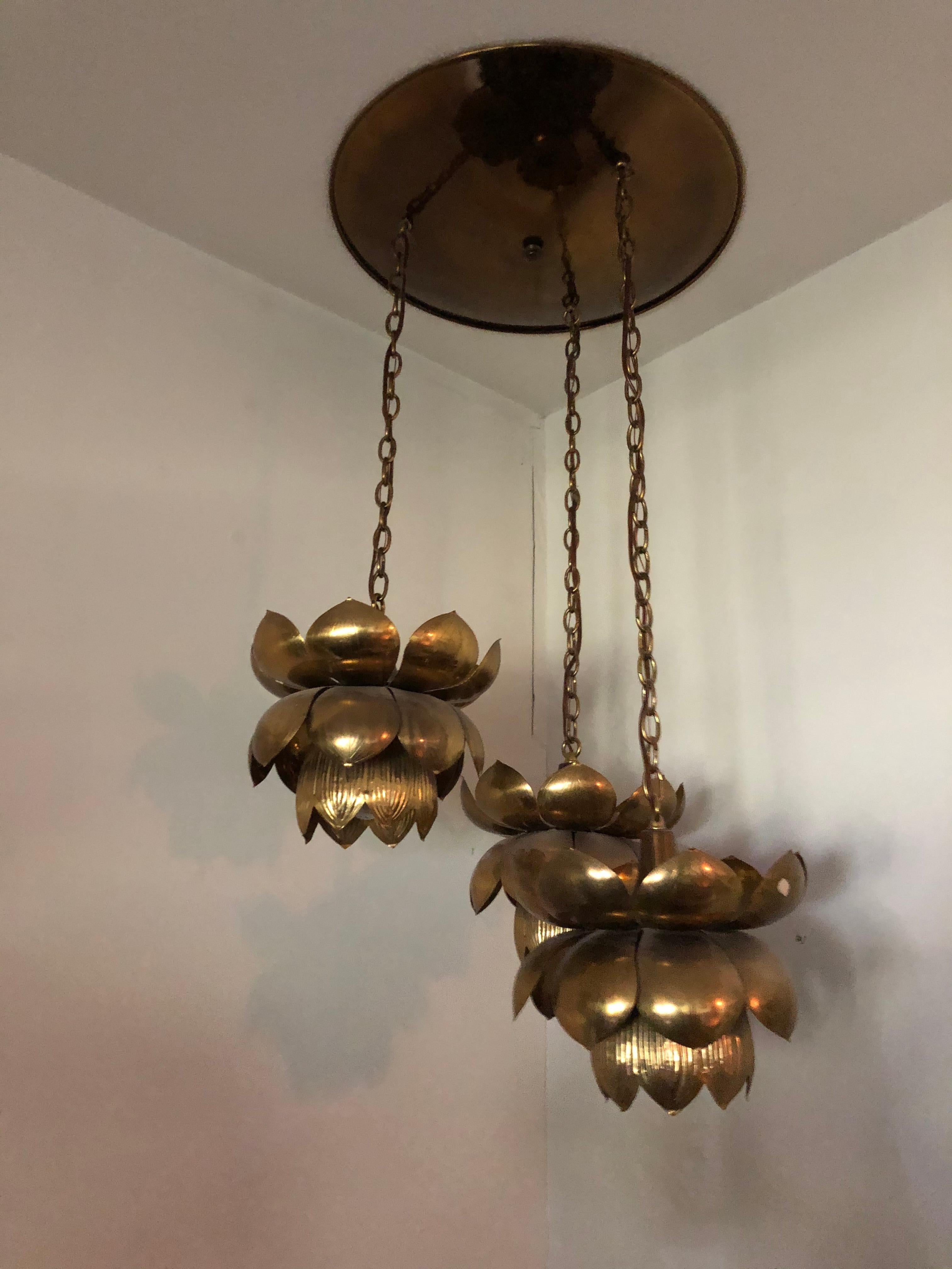 Fantastic trio of the iconic Feldman brass lotus chandelier pendants suspended at different lengths. The brass is etched with gentle ridges on each flower. Original disc ceiling cap included.

