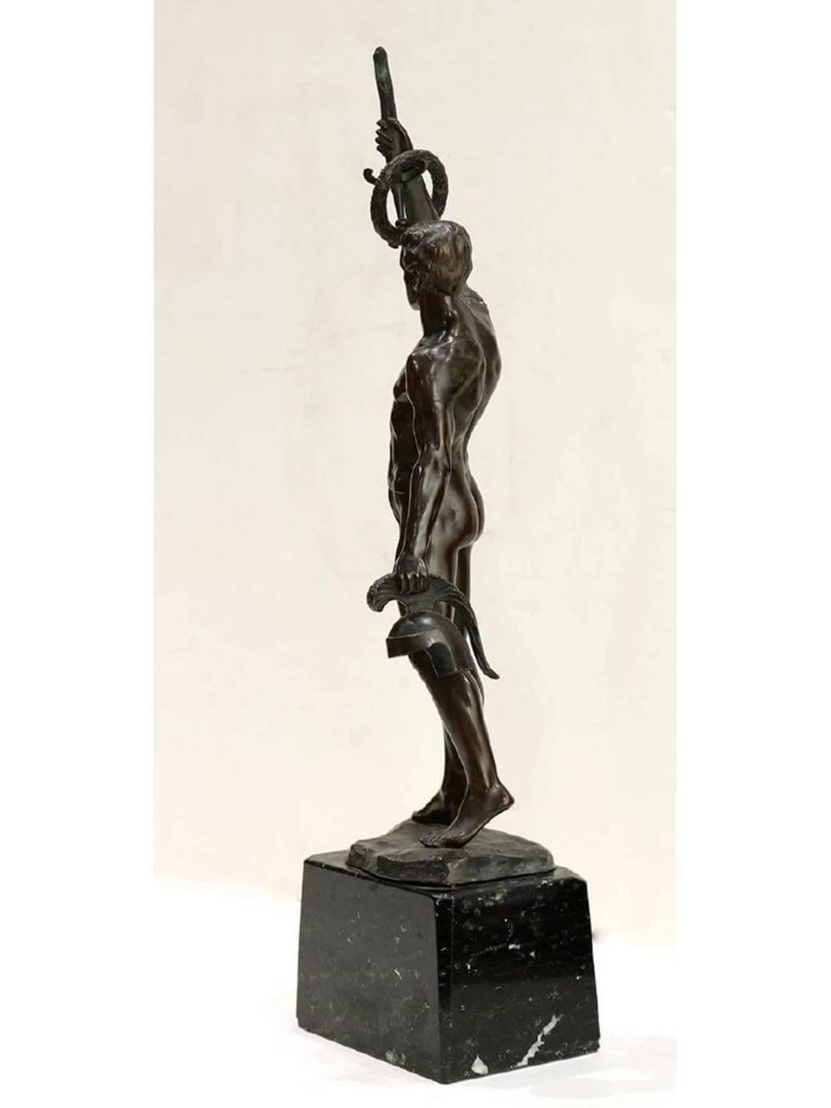 A classical bronze of a muscular Olympic Greek fighting athlete titled “To the Victor”. The athlete has raised a hand holding a sword by its blade with a laurel wreath around the hilt, and is holding his helmet in his other hand. The bronze is by