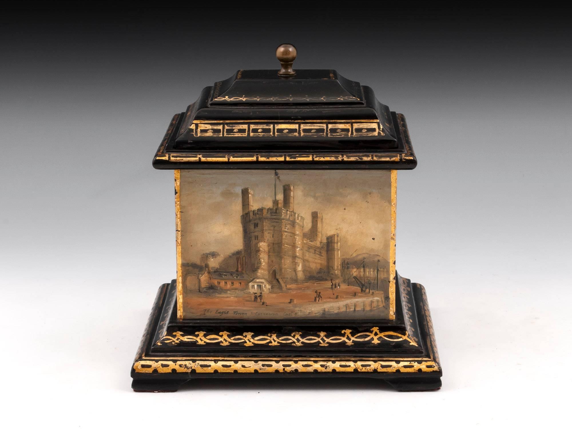 Slate tobacco box with gilt decorated molded plinth and top with turned brass ball handle to its removable lid. The four sides finely painted with Welsh famous landmarks. They comprise: Eagle Tower at Caernarfon Castle, Penryhn Castle, The pass of