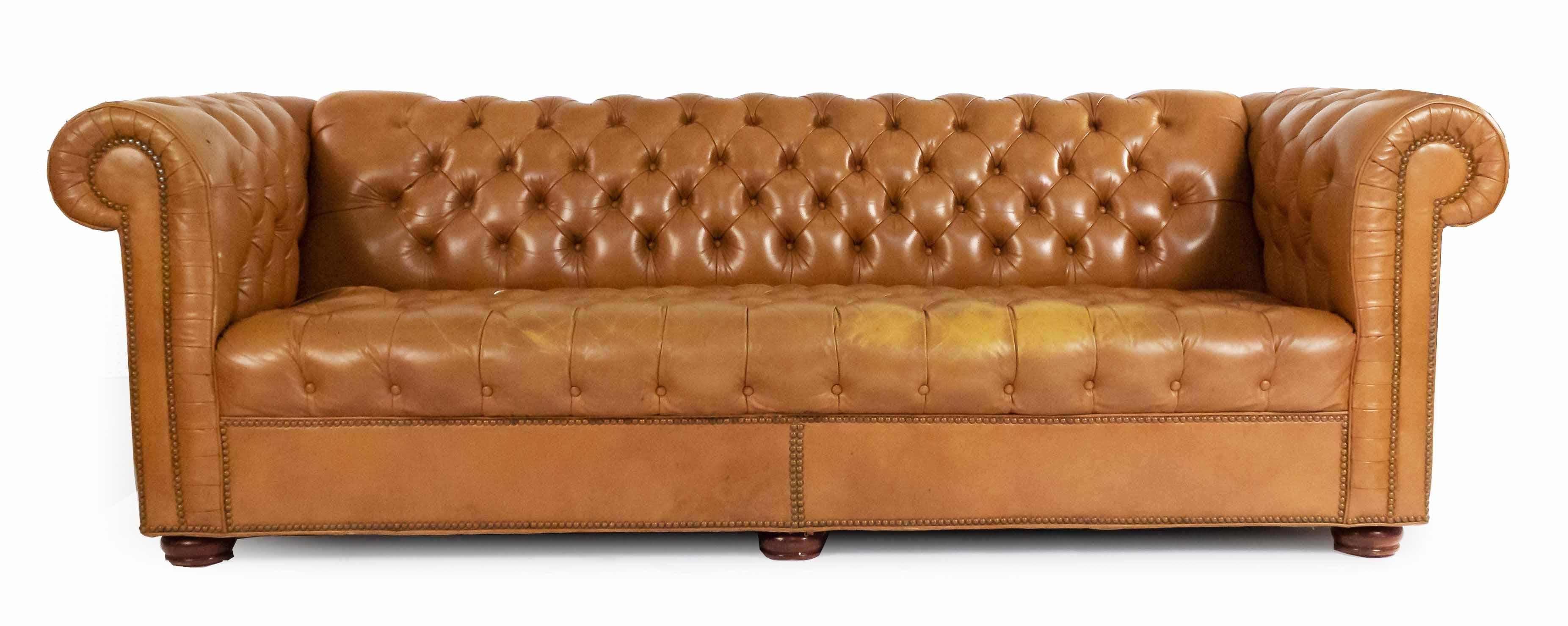 English Victorian style tobacco brown tufted leather chesterfield sofa with out-scrolled arms on four wooden brown feet. Brass rivets along trim.