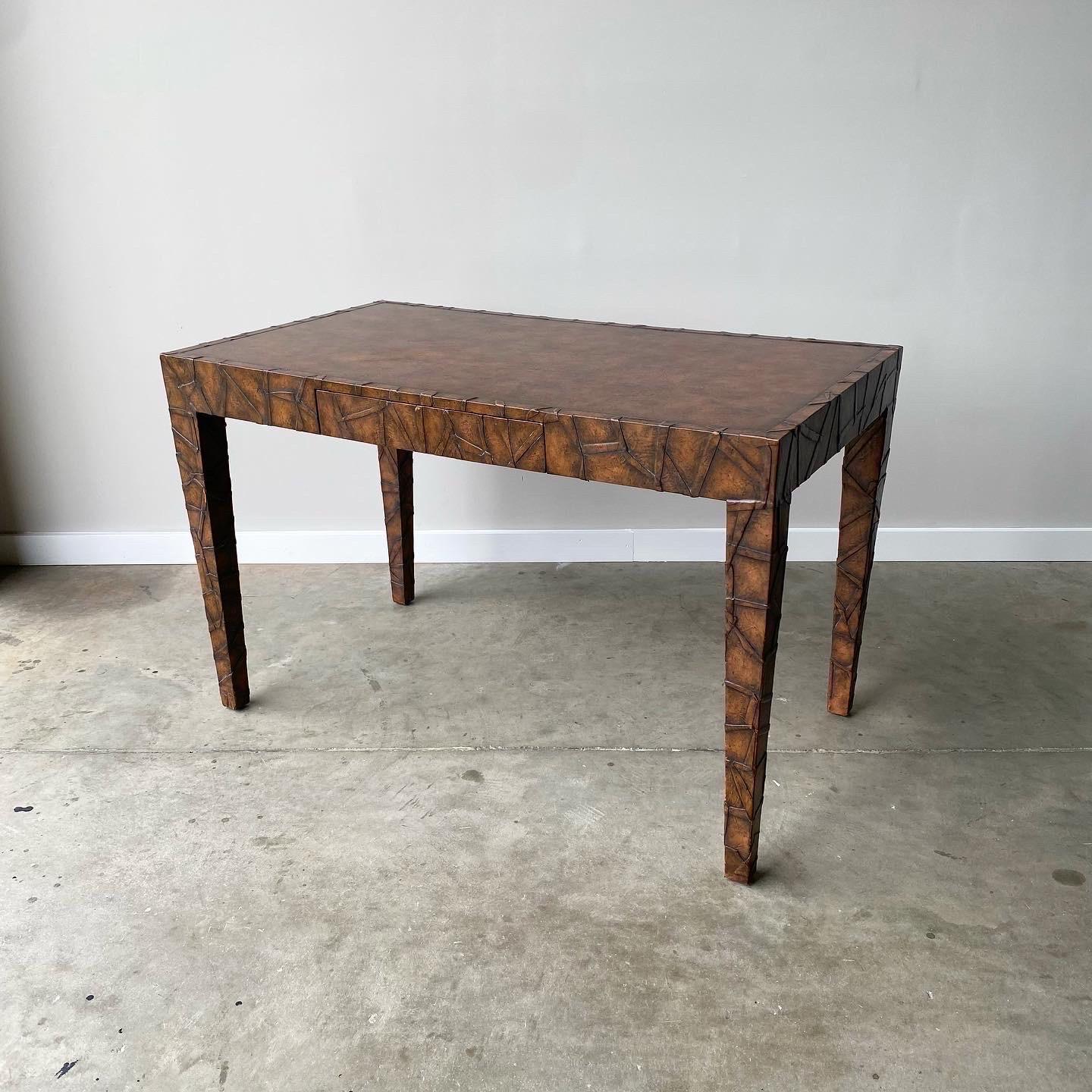 A unique tobacco leaf wrapped desk with pencil drawer.  Circa 1980s and possibly made by Maison Jansen.  This piece is finished on all sides and is in great vintage condition.   