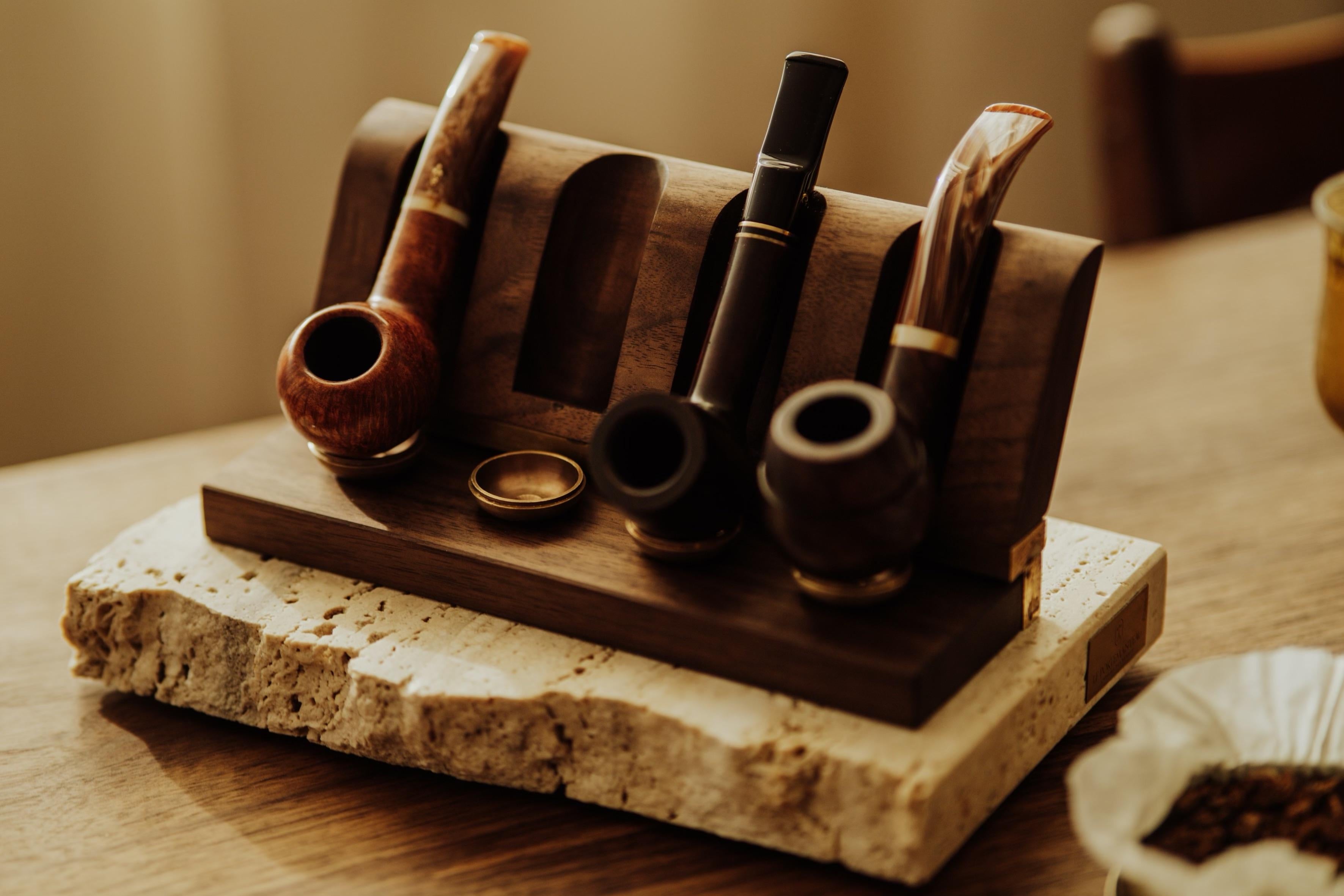 The pipe stand was designed to hold four current pipes in which you smoke your favorite tobacco. It works great as a handy stand on your desk. The solid travertine base adds an organic accent to the stand. The saddle is made of hand-cast brass. The
