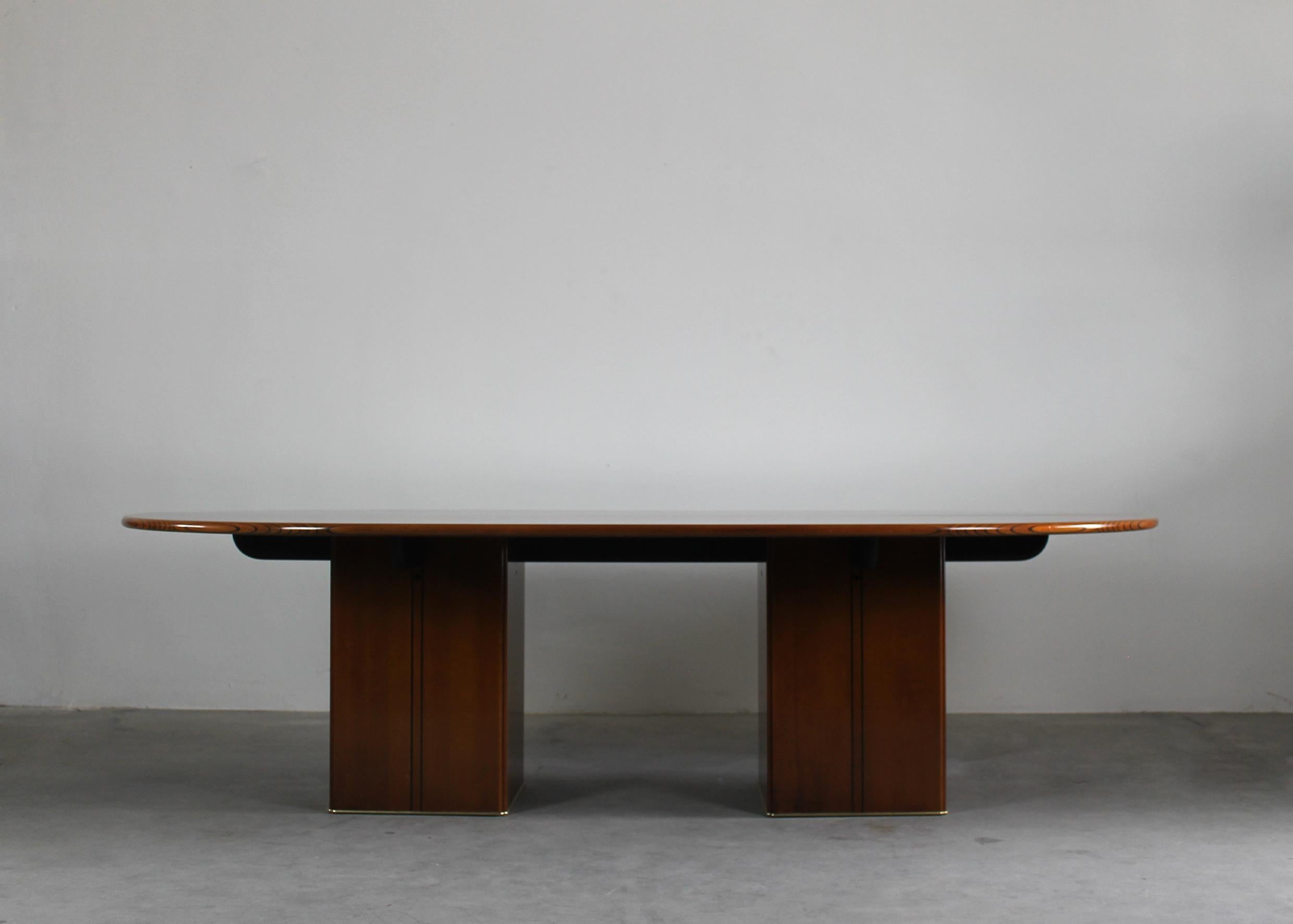 Large oval-shaped table in walnut wood and walnut burl with brass details, the tabletop is made in two pieces which are divided over the length, and it is supported by two square column legs. 

Designed by Tobia and Afra Scarpa for Maxalto