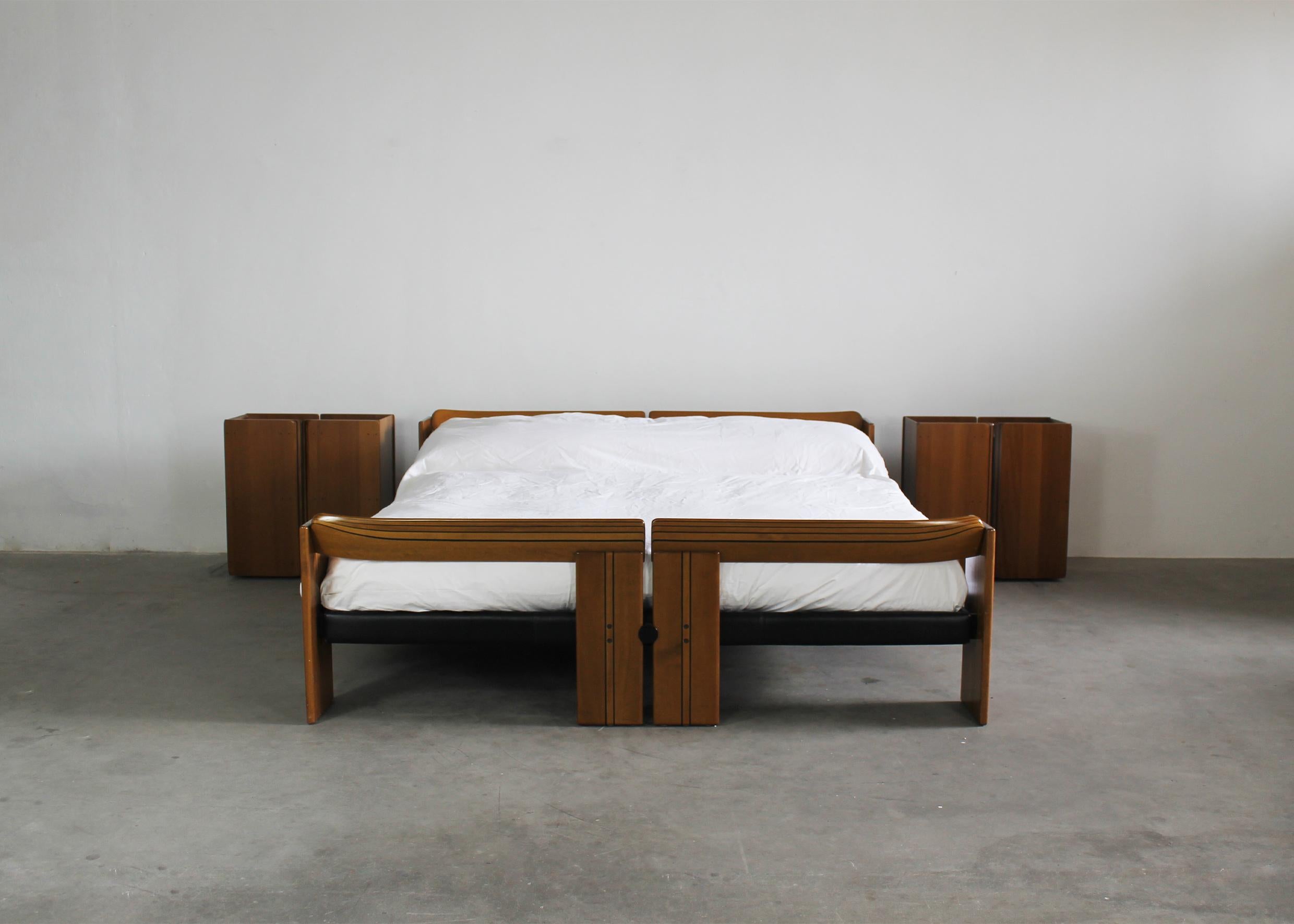 Bedroom set from Artona series composed by one double-bed frame and a couple of nightstands in walnut wood, leather and metal details. 
Designed by Tobia and Afra Scarpa and produced by Maxalto in 1970s. 

The bed-frame is caratcterized by it's