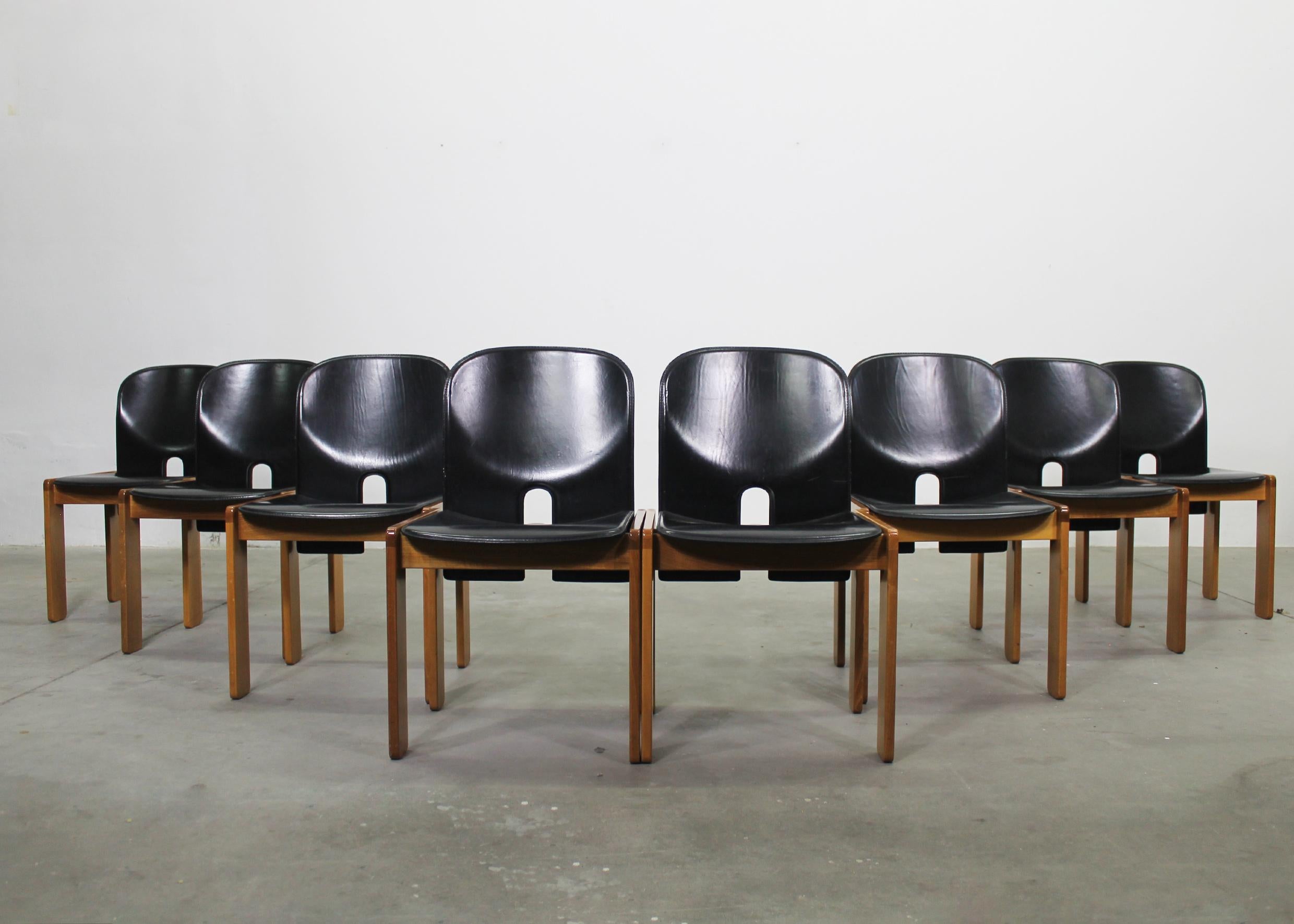 Set di otto sedie 121 con struttura in legno, seduta e schienale in gommapiuma rivestiti in pelle nera.
Disegnata da Tobia & Tobia Scarpa nel 1965 e prodotta da Cassina. 

L'etichetta del produttore è visibile sotto il sedile.

La sedia 121 ha un