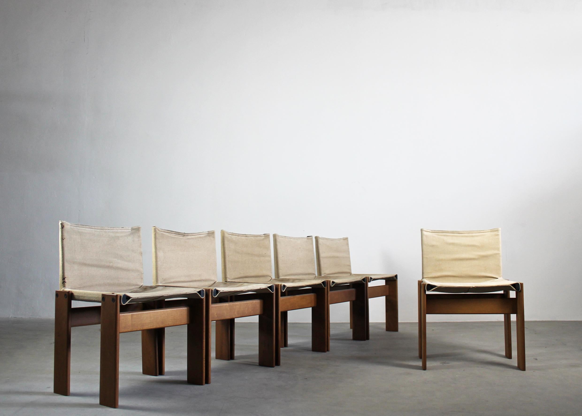 Set of six Monk chairs with a structure in walnut wood, the seat, and the back are made of canvas, which is fitted over two tubular steel sections in such a way as to create a very comfortable chair. 
Made from solid wooden planks, the legs support