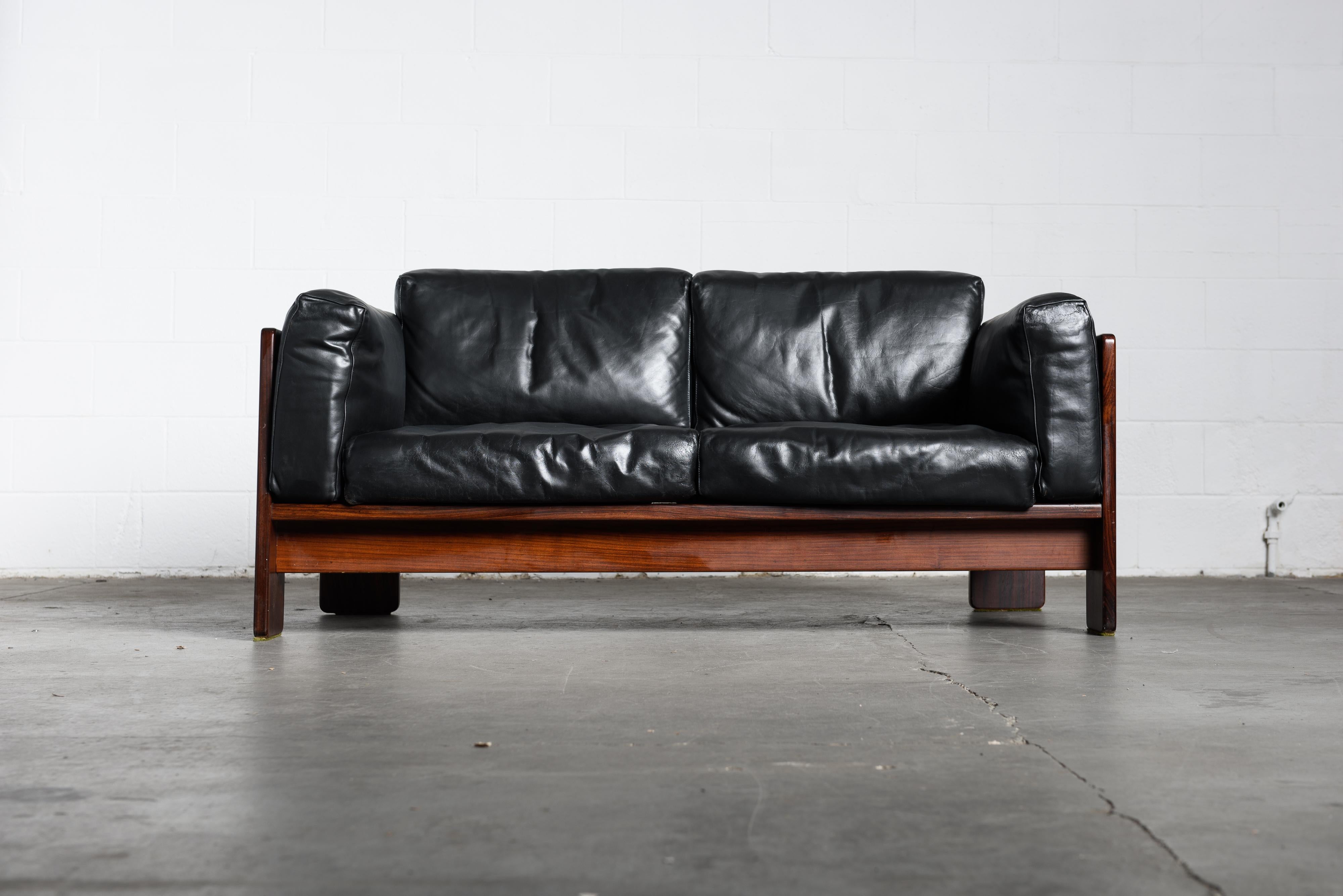 Highly sought after pair of black leather and Brazilian Rosewood 'Bastiano' loveseat sofas by Afra and Tobia Scarpa for Gavina, signed with several Gavina labels. This elegantly crafted sofa has been fabricated from Rosewood which displays a