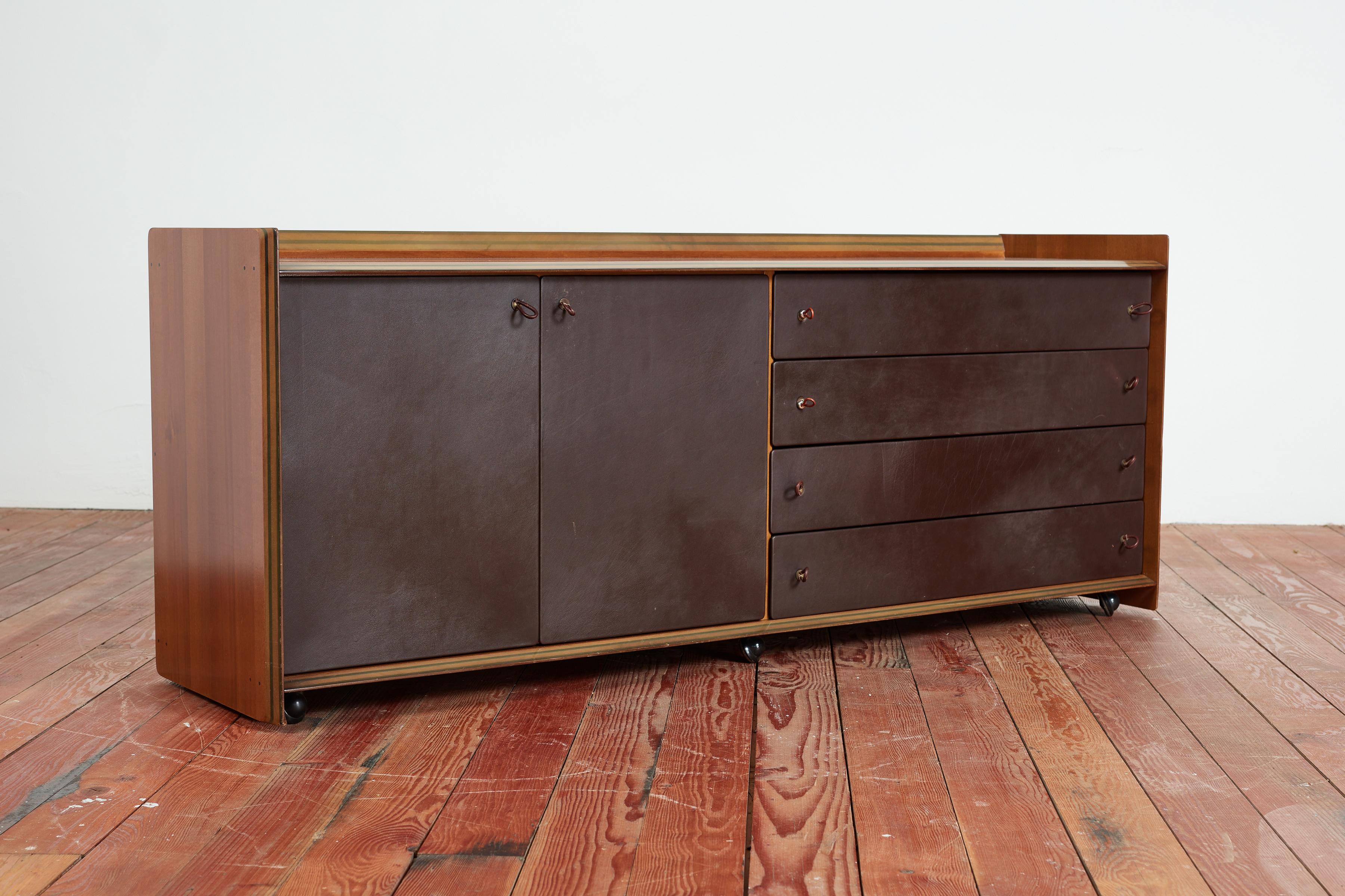 Afra & Tobia Scarpa sideboard for the Artona series for Maxalto. 
Gorgeous chocolate brown leather featuring four drawers with leather loop handles on one side and open door storage on the other. 
Wonderful patina with signature wheels 
Italy, 1975