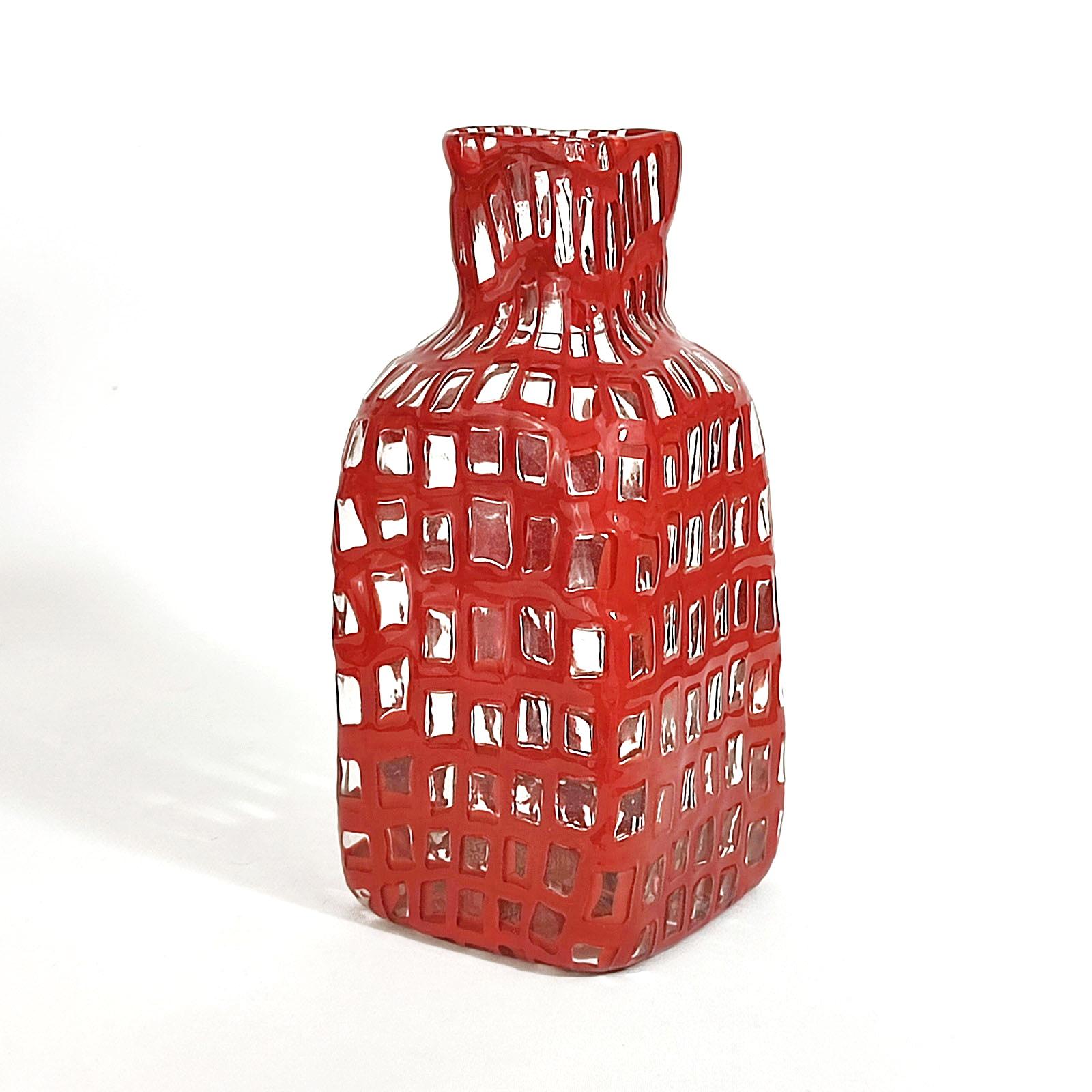 Tobia Scarpa 'Occhi' Flasche, Venini, Italien, 1960er Jahre.
Farbloses Glas, rot umrandete Murine, schachbrettartig angeordnet und verschmolzen. Viereckige Form, an den Ecken abgerundet, quadratischer Hals. In ausgezeichnetem Zustand.
Gezeichnet: