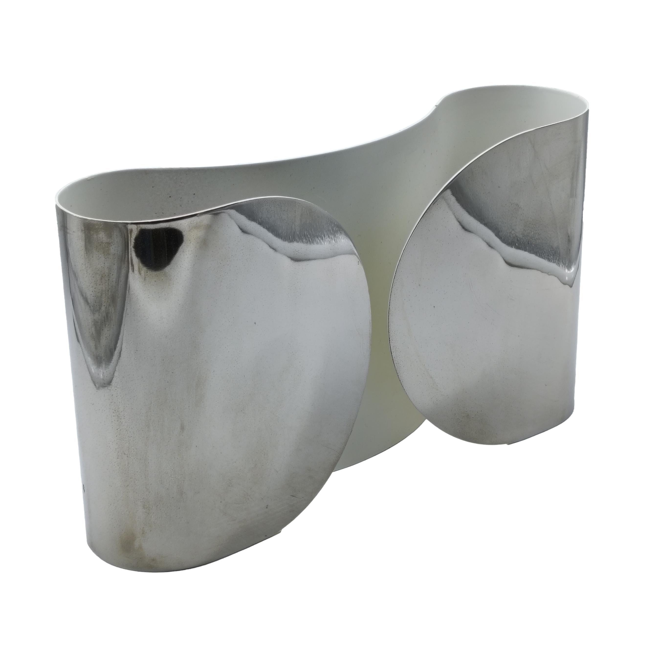 Aplique 'Foglio' diseñado por Tobia Scarpa para Flos. Fabricado a partir de una única lámina de metal curvado, el Foglio tiene una forma suave y orgánica que recuerda a un sobre doblado. Su diseño es a la vez escultural y práctico: la lámpara