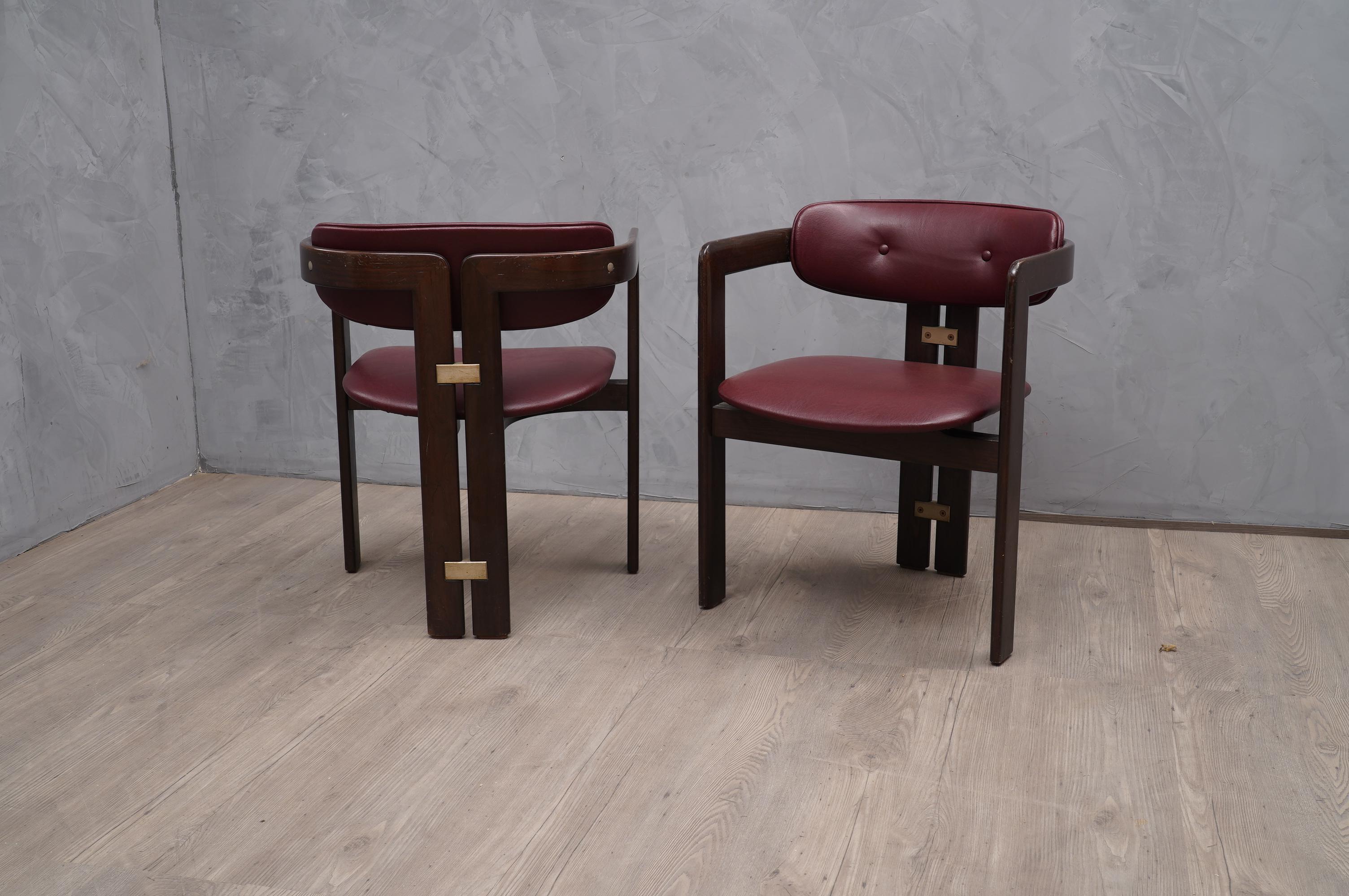 Wonderful pair of chairs with armrests, due both to the design of the structure and to the use of fine materials.

The chairs are formed by two wooden structures joined at the rear by two metal inserts and at the front by a wooden loop on which the