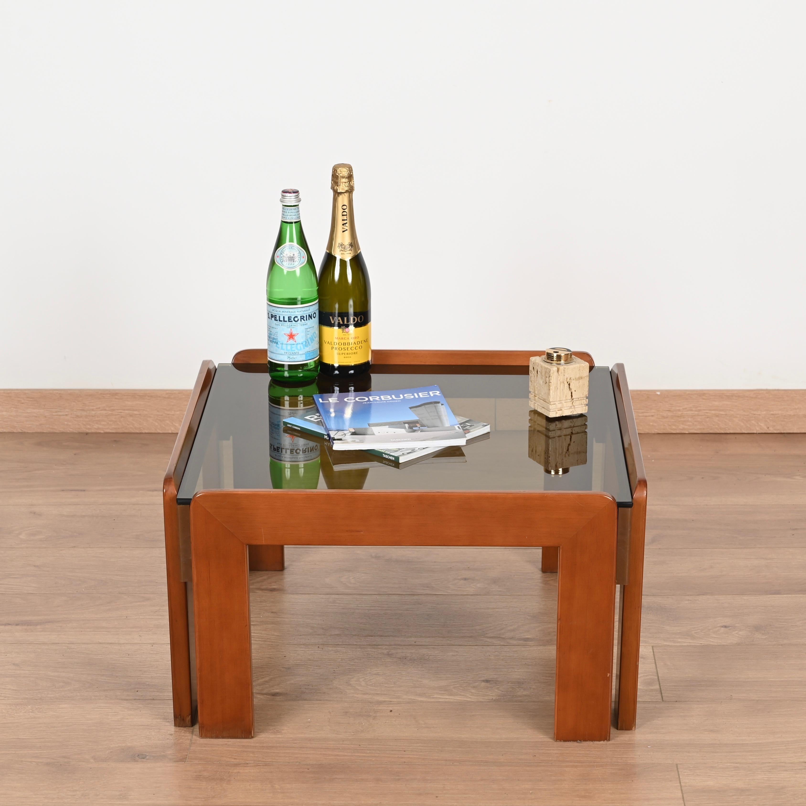Splendido tavolino quadrato di metà secolo in legno di noce con piano in vetro fumé. Questo tavolino incredibilmente bello è stato prodotto in Italia negli anni '60 da Cassina e disegnato da Afra & Tobia Scarpa.

Questo elegante tavolino da caffè è