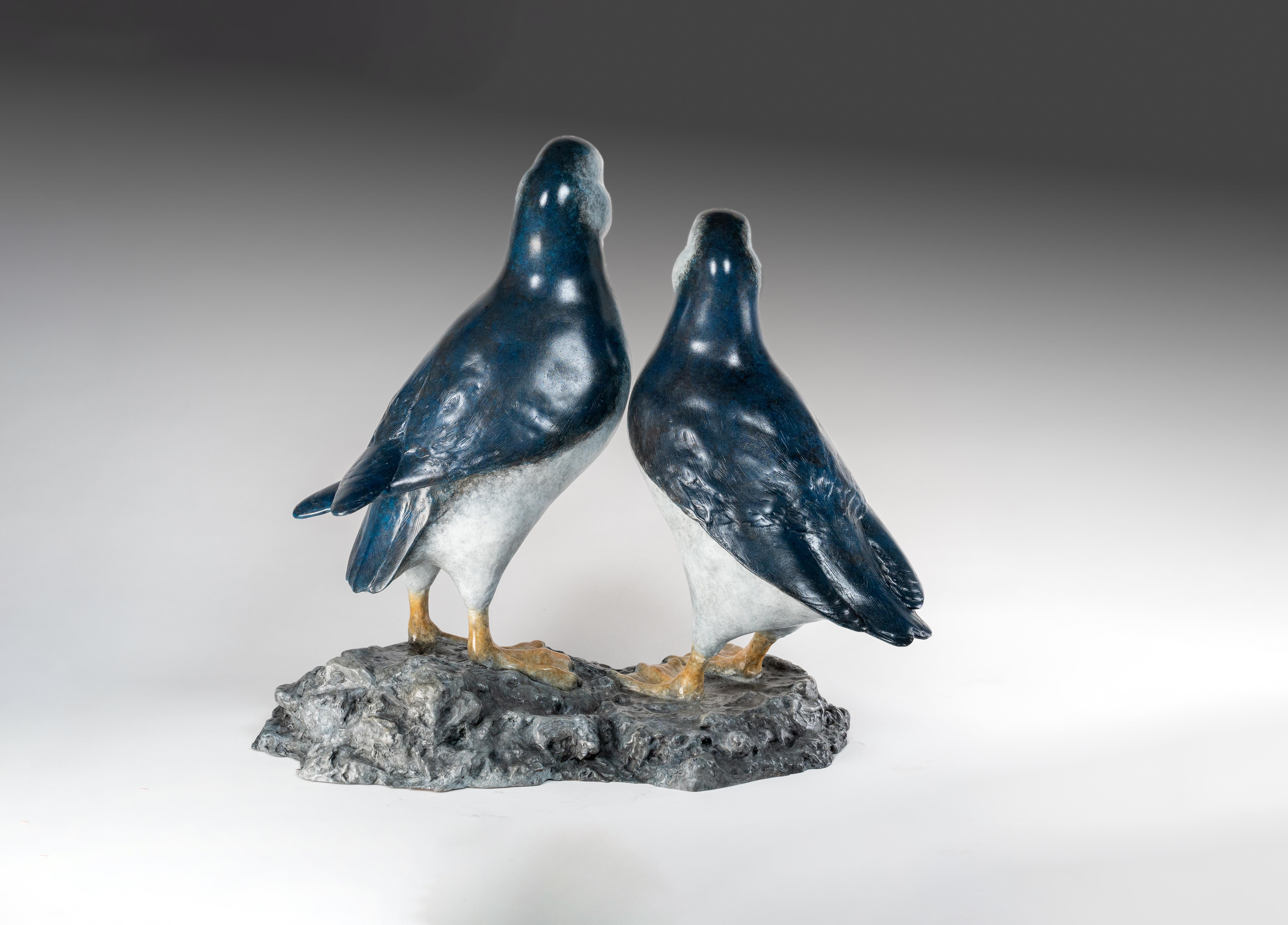 'Best Friends' by Tobias Martin is a Solid Bronze Animal Sculpture of a pair of puffins on rocks, amaxing blue patina with white and orange bill. 

Tobias Martin was born in 1972 in Wiltshire, 12 miles from Stonehenge. Influenced by his idyllic