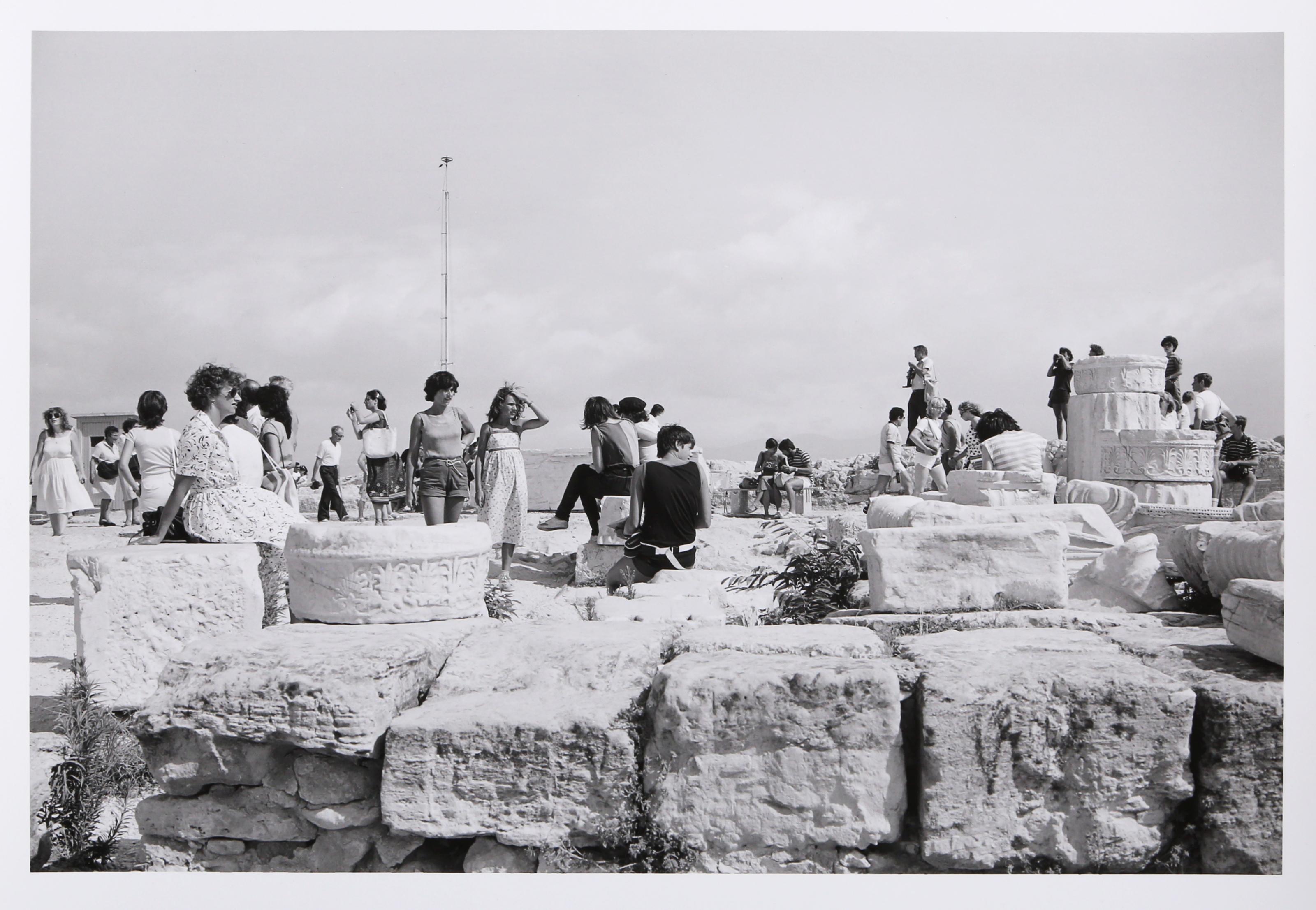 Tourists and Marble Fragments is a gelatin silver print from On the Acropolis, a portfolio of 25 photographs by Tod Papageorge made on the Athenian Acropolis in the summers of 1983 and 1984. The image depicts tourists dispersed across the plateau