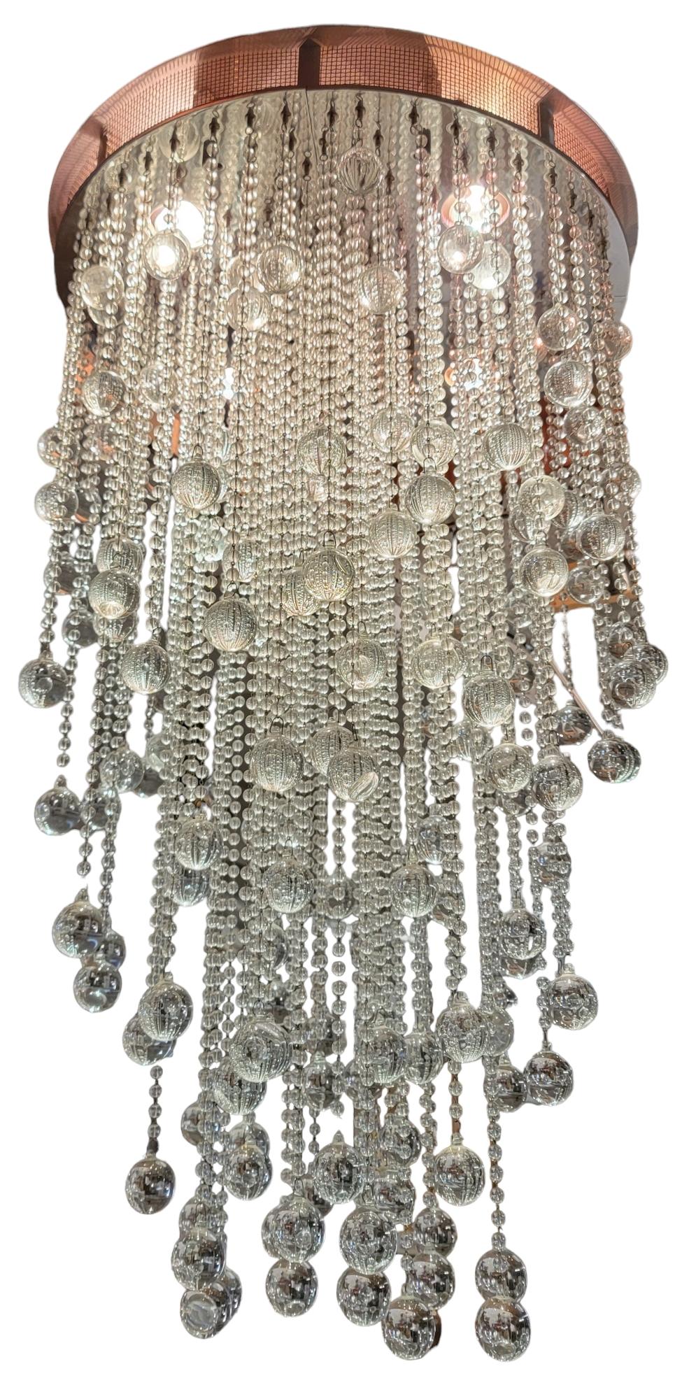 Stunning Todd Rugee Large chandelier. The lights are  LED lights within the frame that shin down on the hanging beads Each Bead has one larger crystal ball at the bottom The Frame us made chrome that adds a depth to the sconces. The bead have a