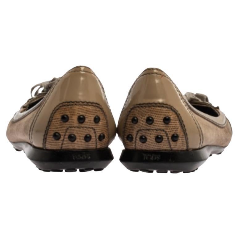 These Tod’s flats are chic, stylish, and highly versatile. Crafted in beige patent and lizard-embossed leather, these sandals feature a suede bow detailing at the vamps with subtle hints of silver-tone hardware. They are complete with durable rubber