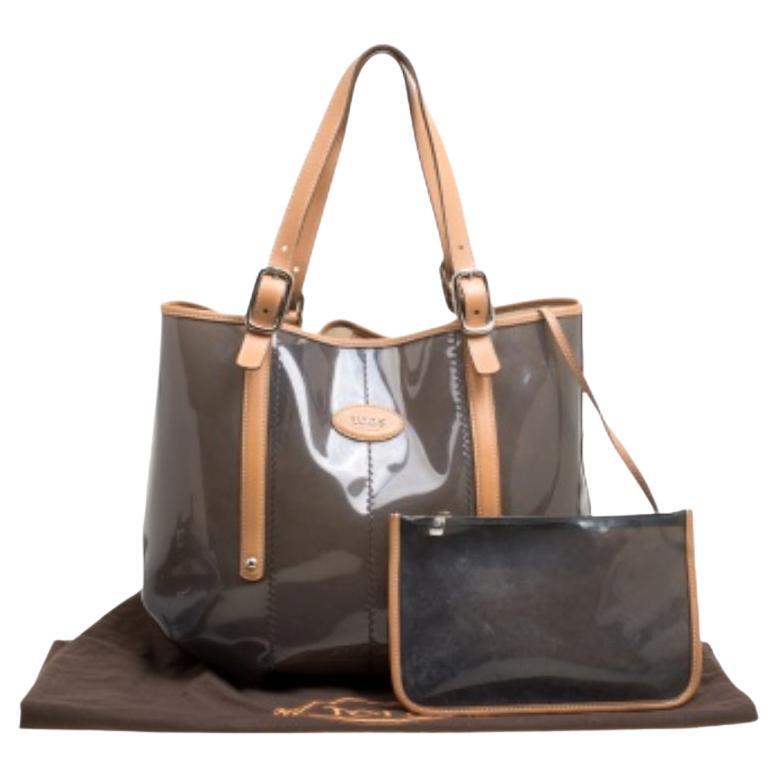 Este bolso de Tod's está pensado para que lleves todo lo que necesitas con facilidad. Fabricado con PVC y adornos de piel, el bolso se sujeta con dos asas de hebilla y va acompañado de una bolsa. Se completa con un interior espacioso.
